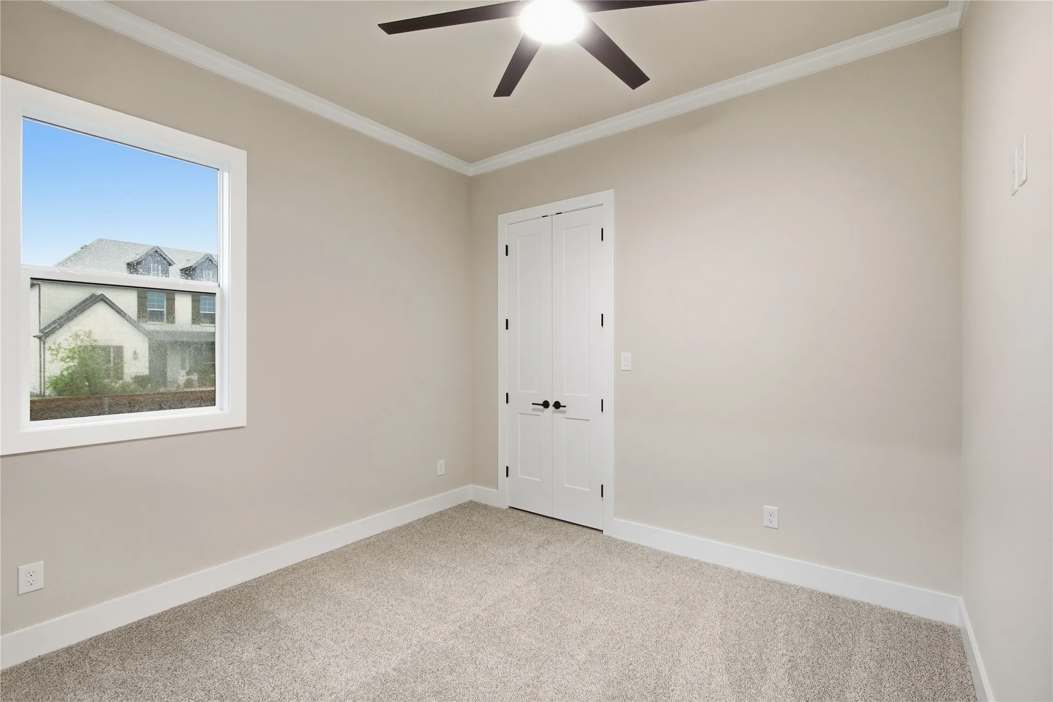 Neutral-toned walls, crown molding, double-door closet, ceiling fan, and carpeted flooring