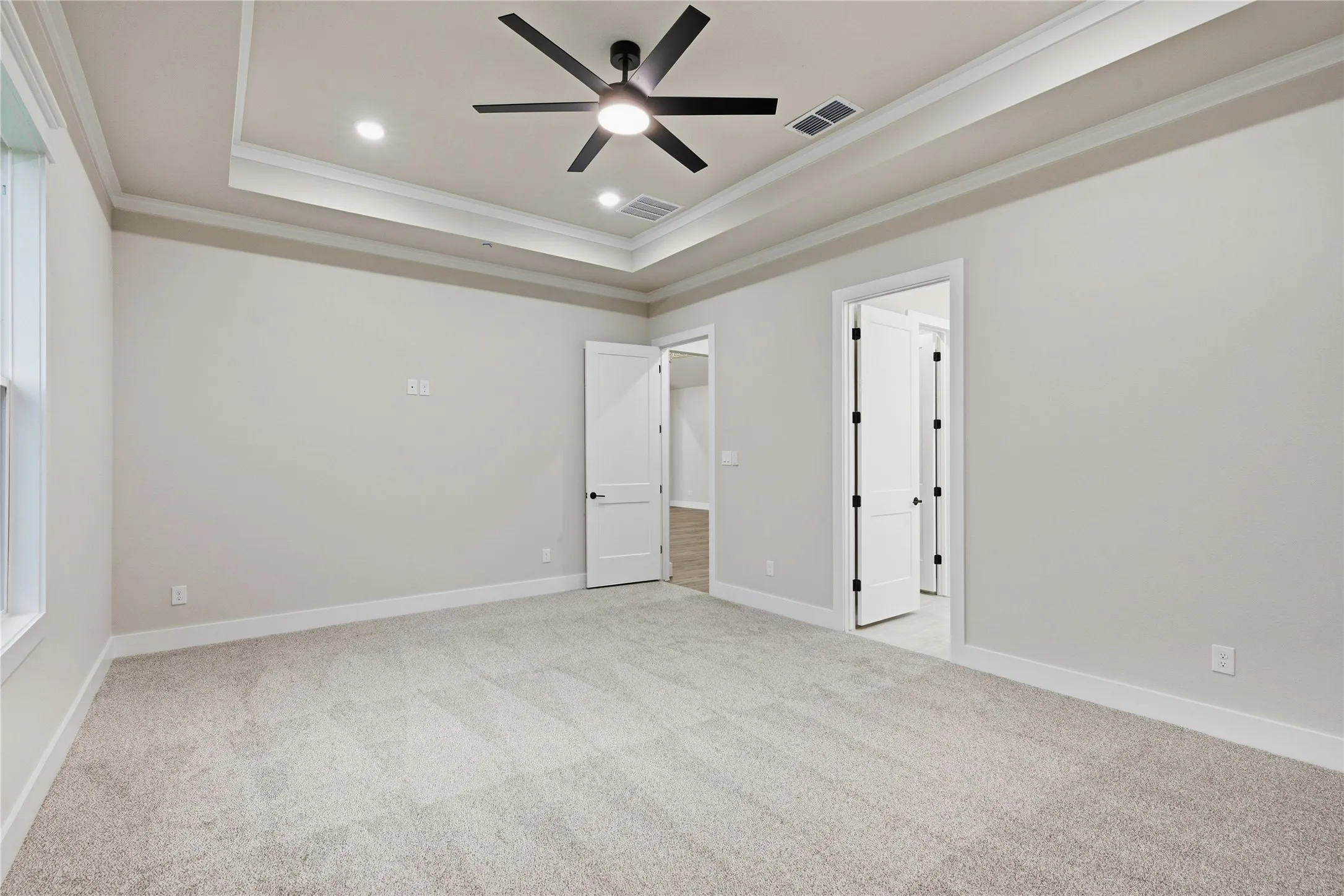 Tray ceiling with crown molding, recessed lighting, ceiling fan, and carpeted flooring
