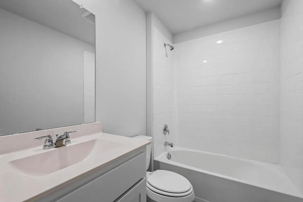 Bathroom featuring a white subway tile shower surround, chrome fixtures, a built-in vanity with a light-colored countertop, and an integrated sink