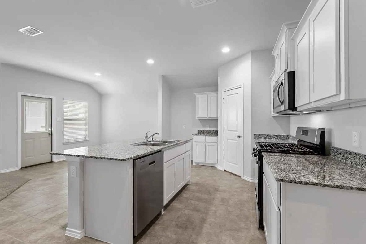 Kitchen featuring an island with double sink, stainless steel dishwasher, granite countertops, and white shaker-style cabinetry