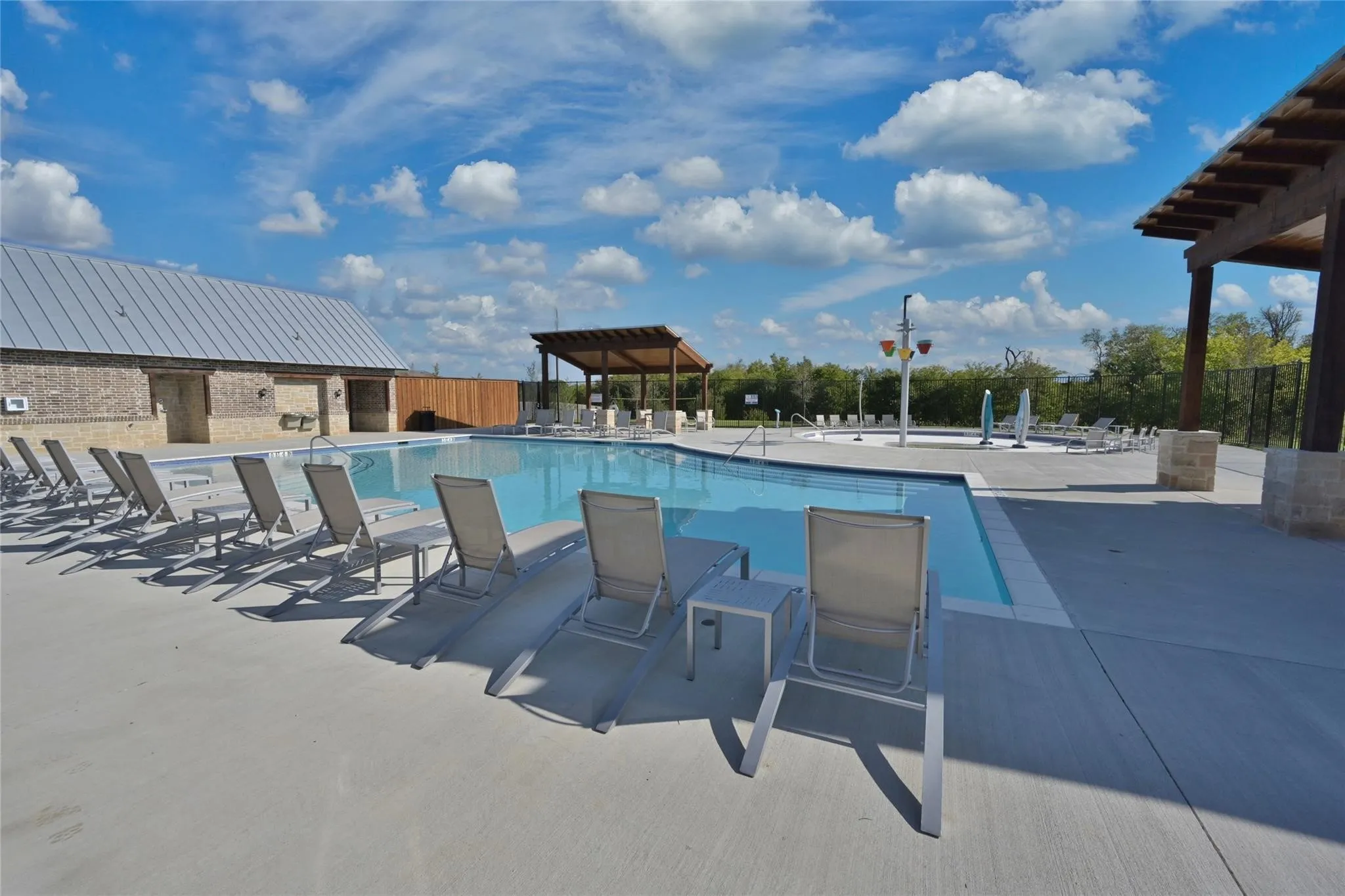 Resort-style pool area featuring a large swimming pool, surrounding concrete decking, and multiple lounge chairs