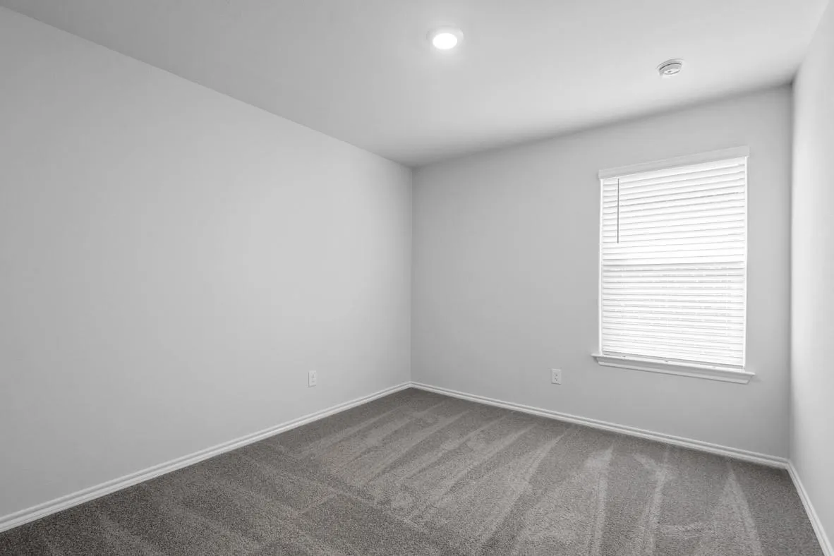 Neutral-toned interior room featuring light gray walls, plush gray carpeting, and white trim