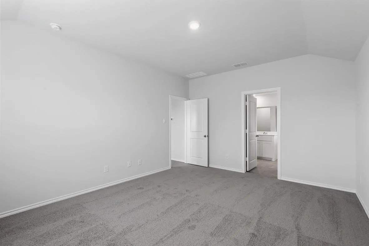 Spacious room featuring light gray carpeting, white painted walls, and a vaulted ceiling with recessed lighting