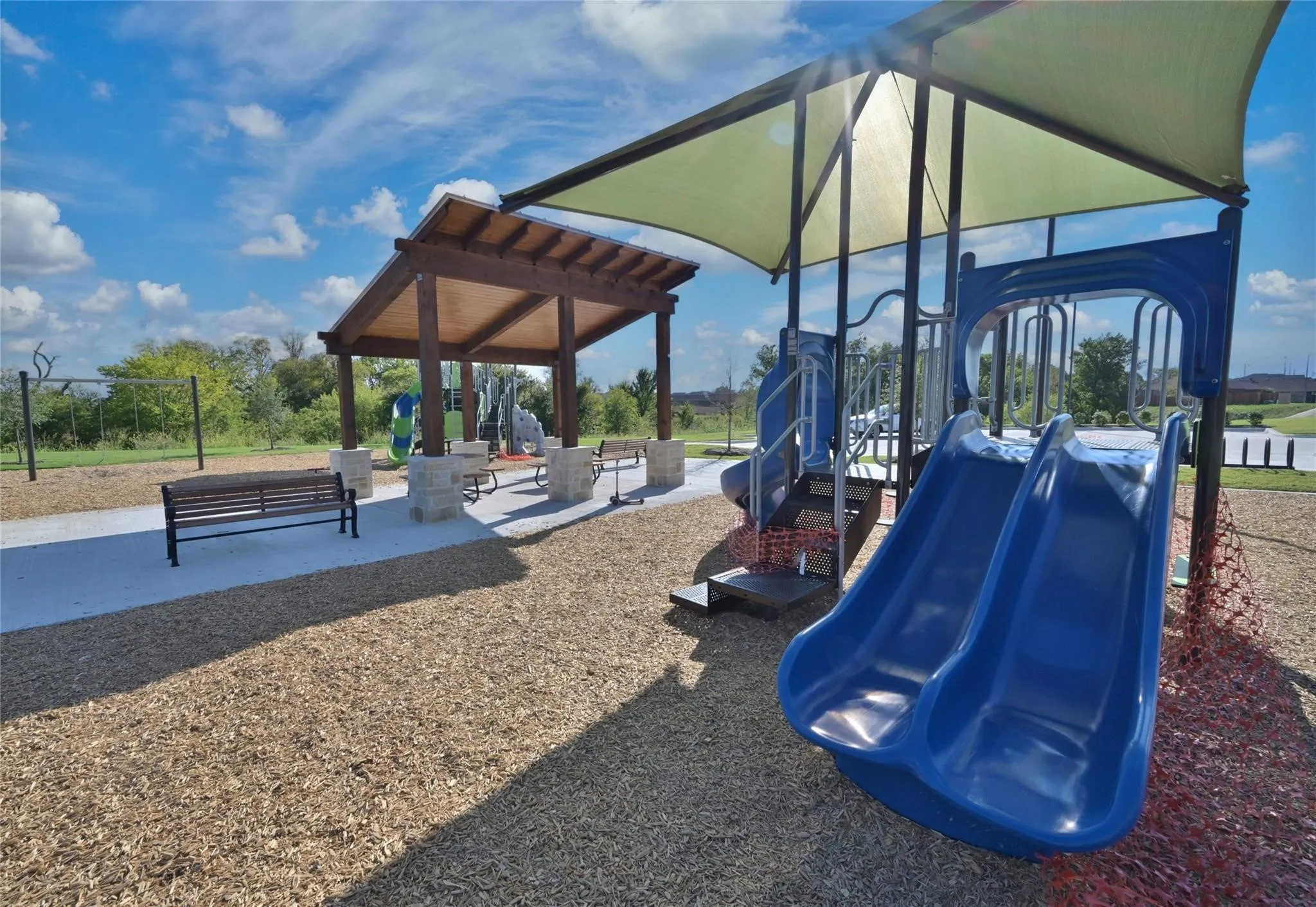 Outdoor play structure featuring dual blue slides and a shaded platform