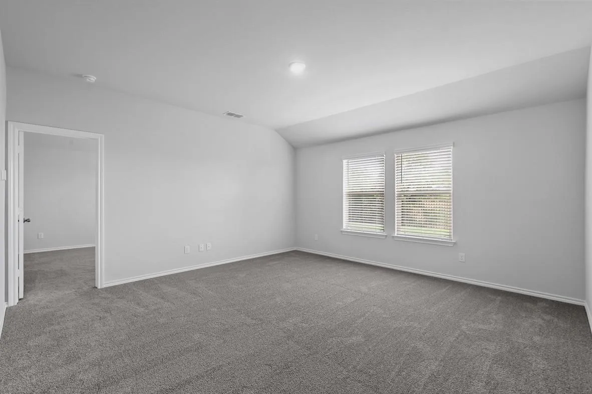 Spacious room featuring gray carpeting, white walls, and two windows with horizontal blinds