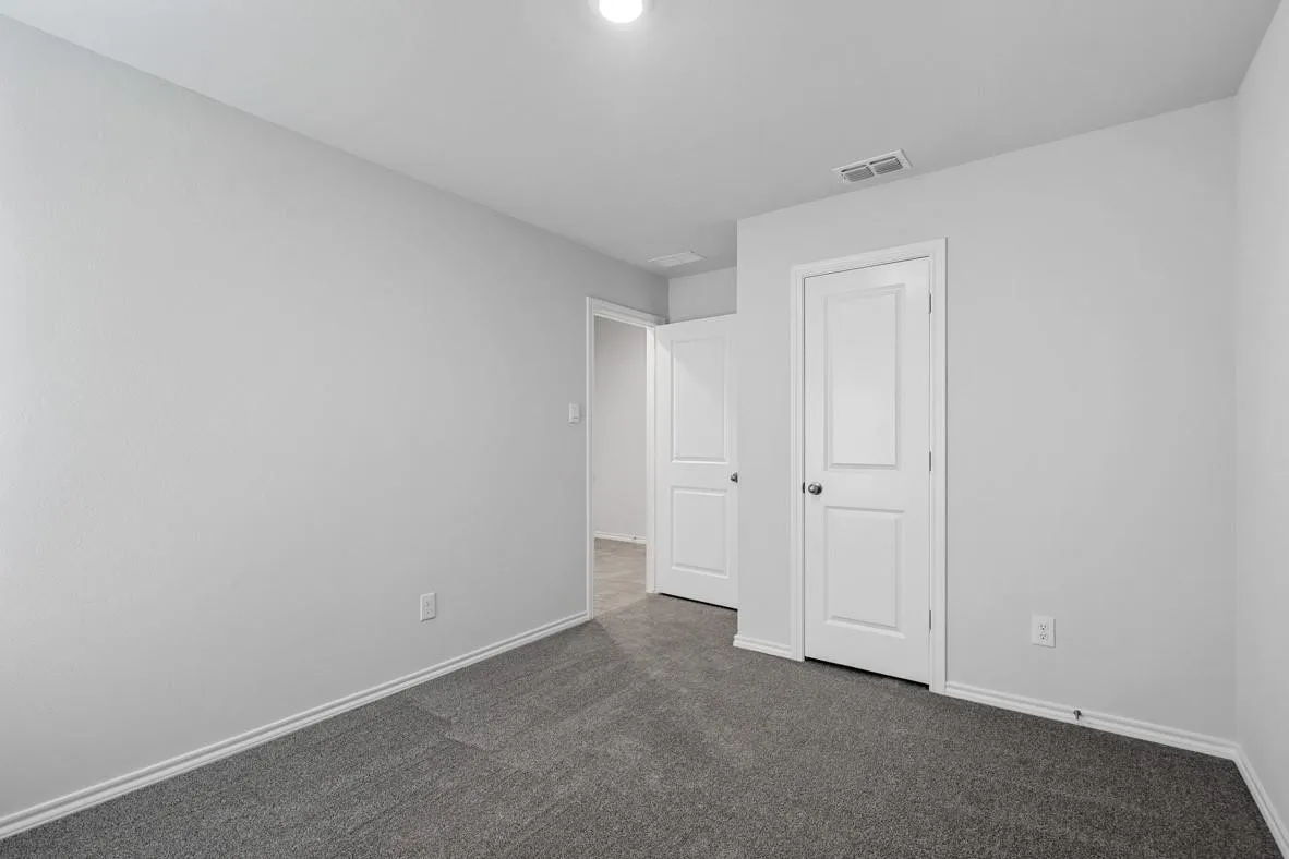 Neutral-toned interior room featuring light gray walls, dark gray carpeting, and white trim