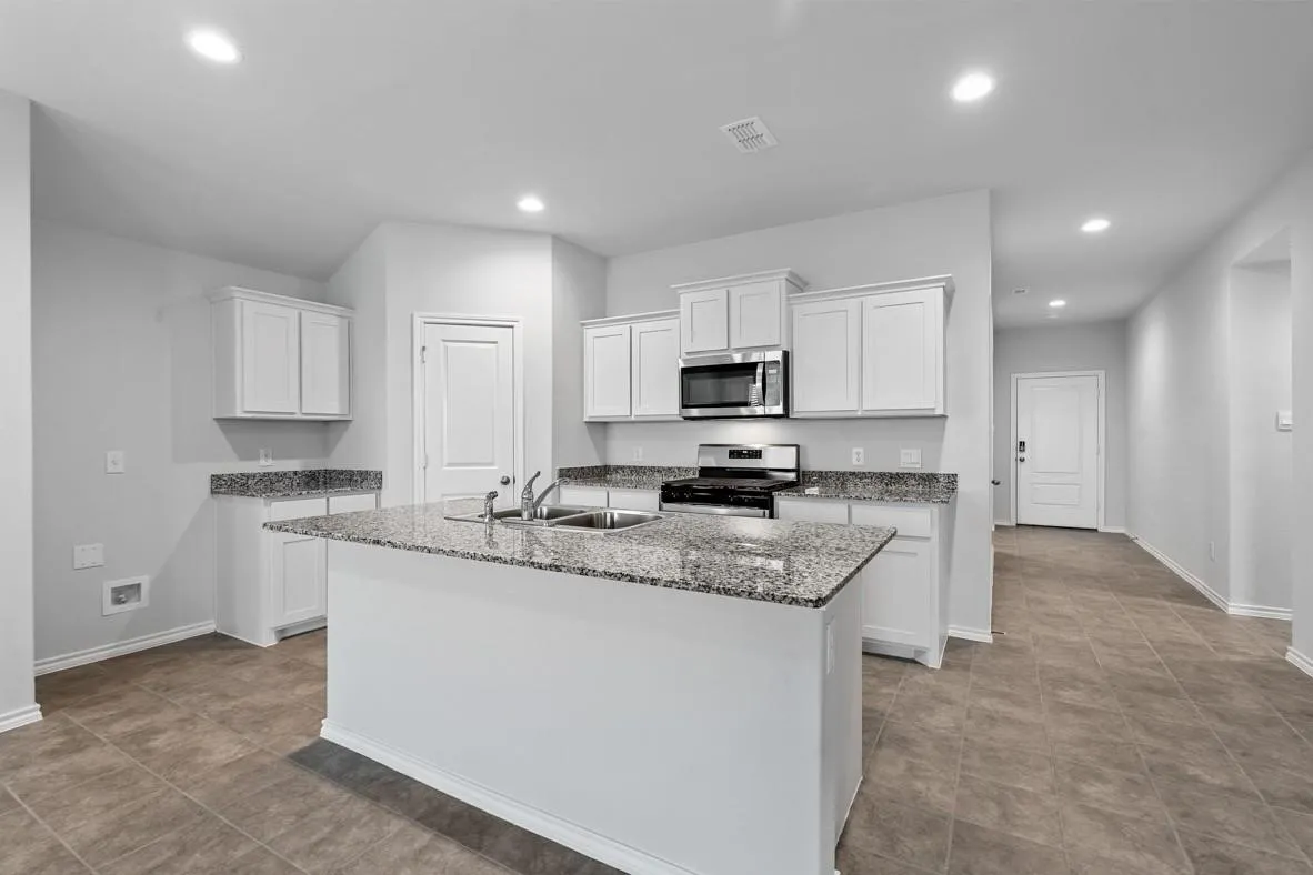 Contemporary kitchen featuring a central island with an undermount double sink, granite countertops, white cabinetry, stainless steel appliances, and recessed lighting