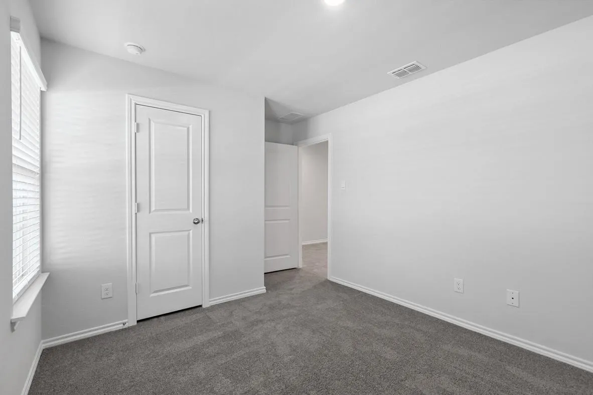 Carpeted room featuring light gray walls, white baseboards, and a white paneled door
