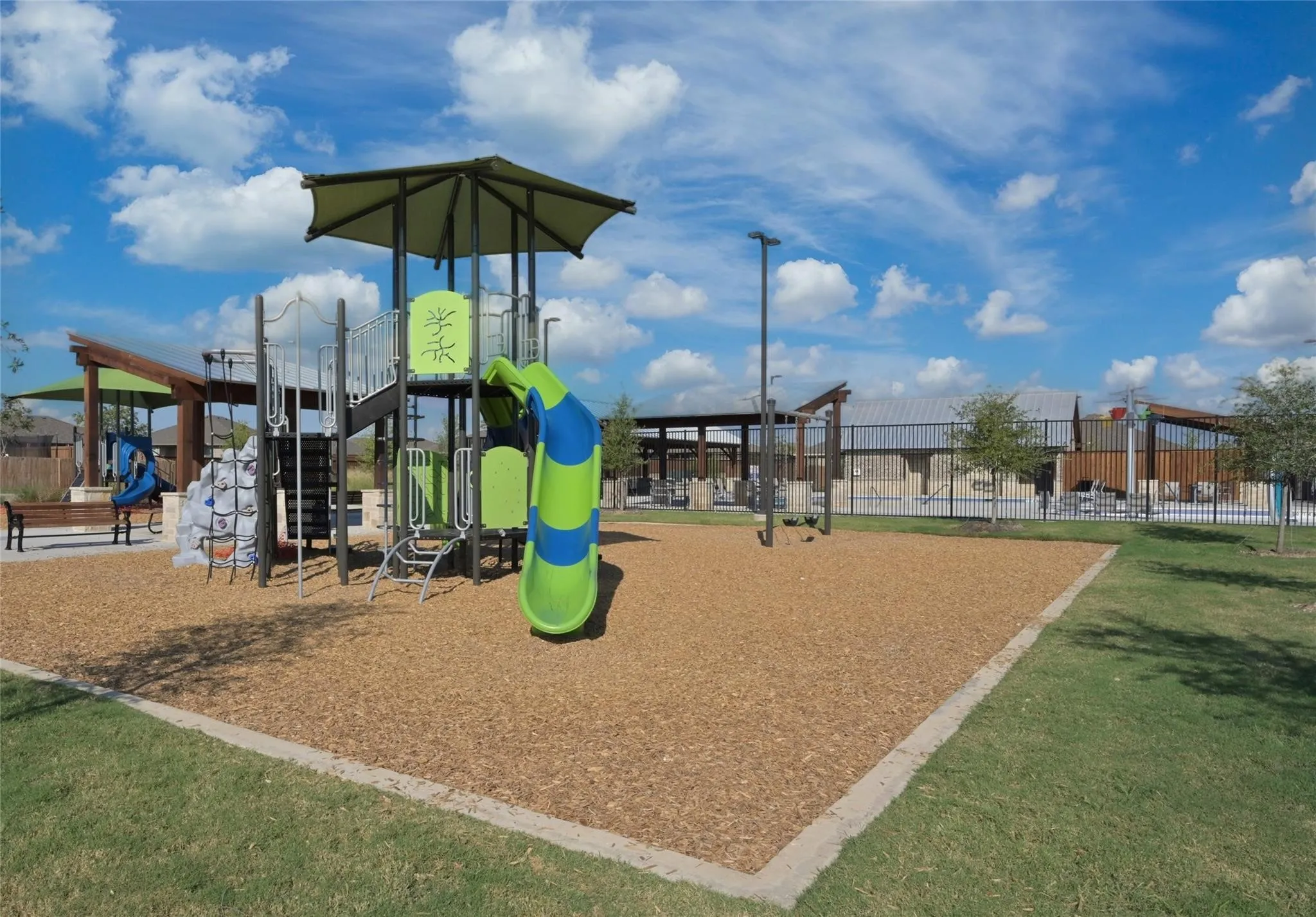 Playground area featuring a multi-level structure with slides and climbing elements set on a wood chip surface