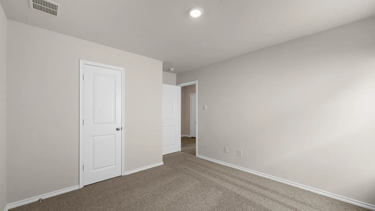 Neutral-toned wall paint with white baseboards, plush carpet flooring, recessed ceiling lighting, and a paneled interior door with chrome hardware
