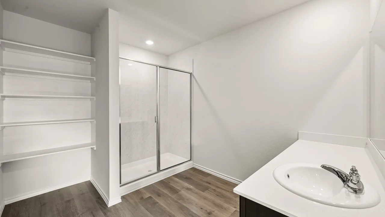 Bathroom featuring a glass-enclosed shower, built-in shelving, a single vanity with an integrated sink, polished chrome faucet, and wood-finish flooring