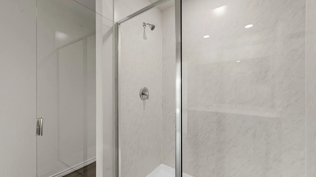 Shower enclosure featuring clear glass panels, a chrome frame, and a chrome shower head and control