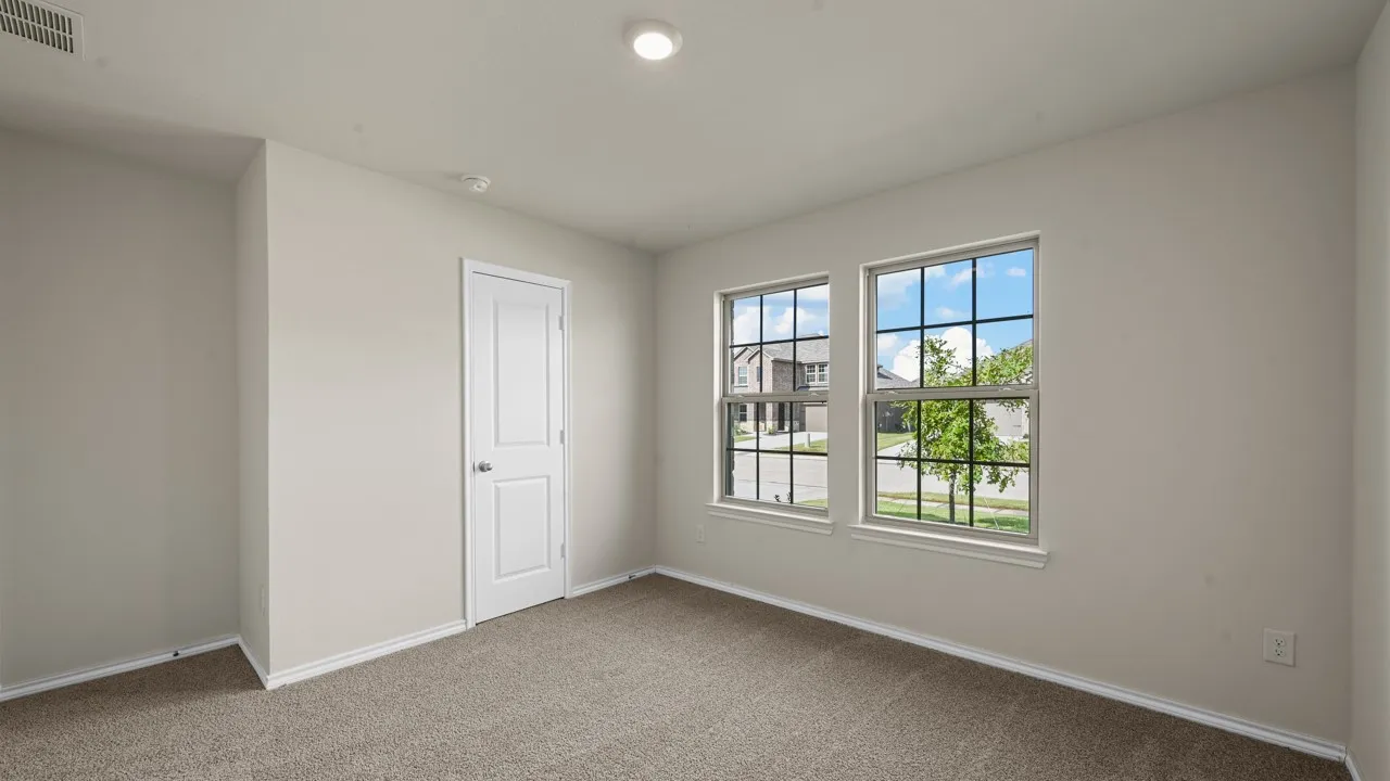 Neutral-toned room featuring two grid-pattern windows, light beige carpeting, white trim, a recessed ceiling light, and a white interior door with a brushed nickel knob