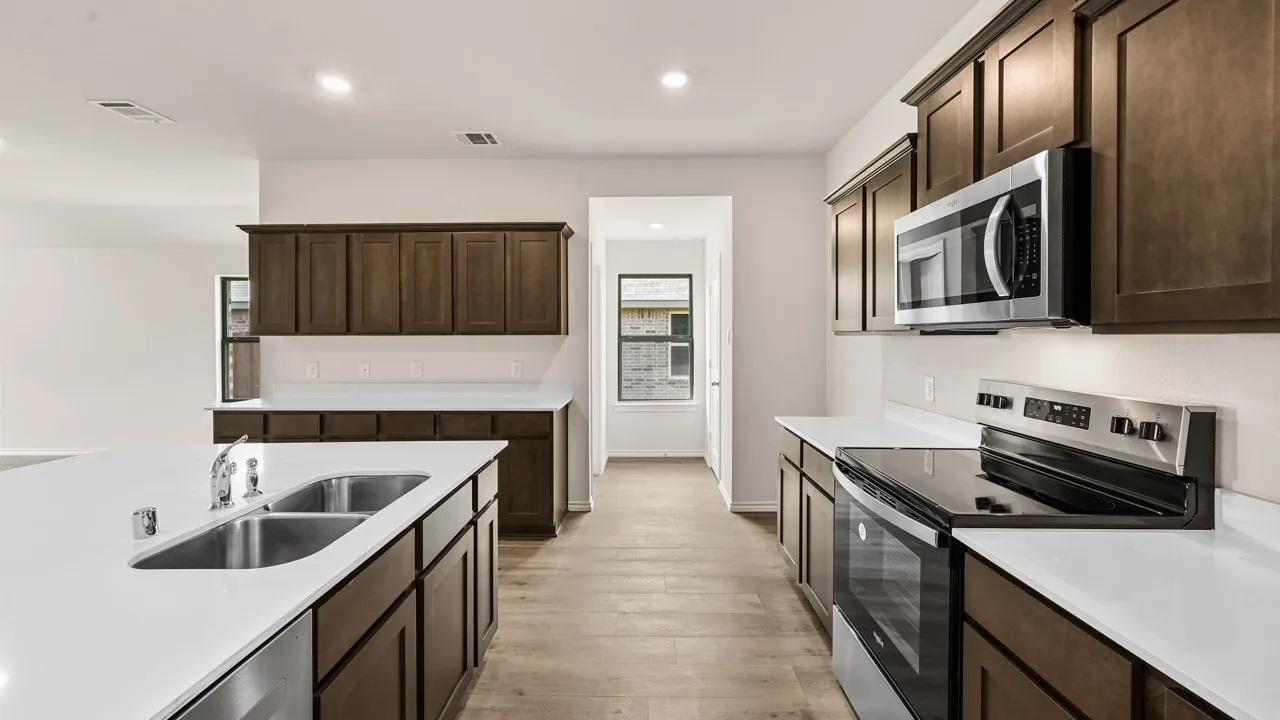 Kitchen featuring dark wood cabinetry, white countertops, stainless steel appliances, and wood-finish flooring