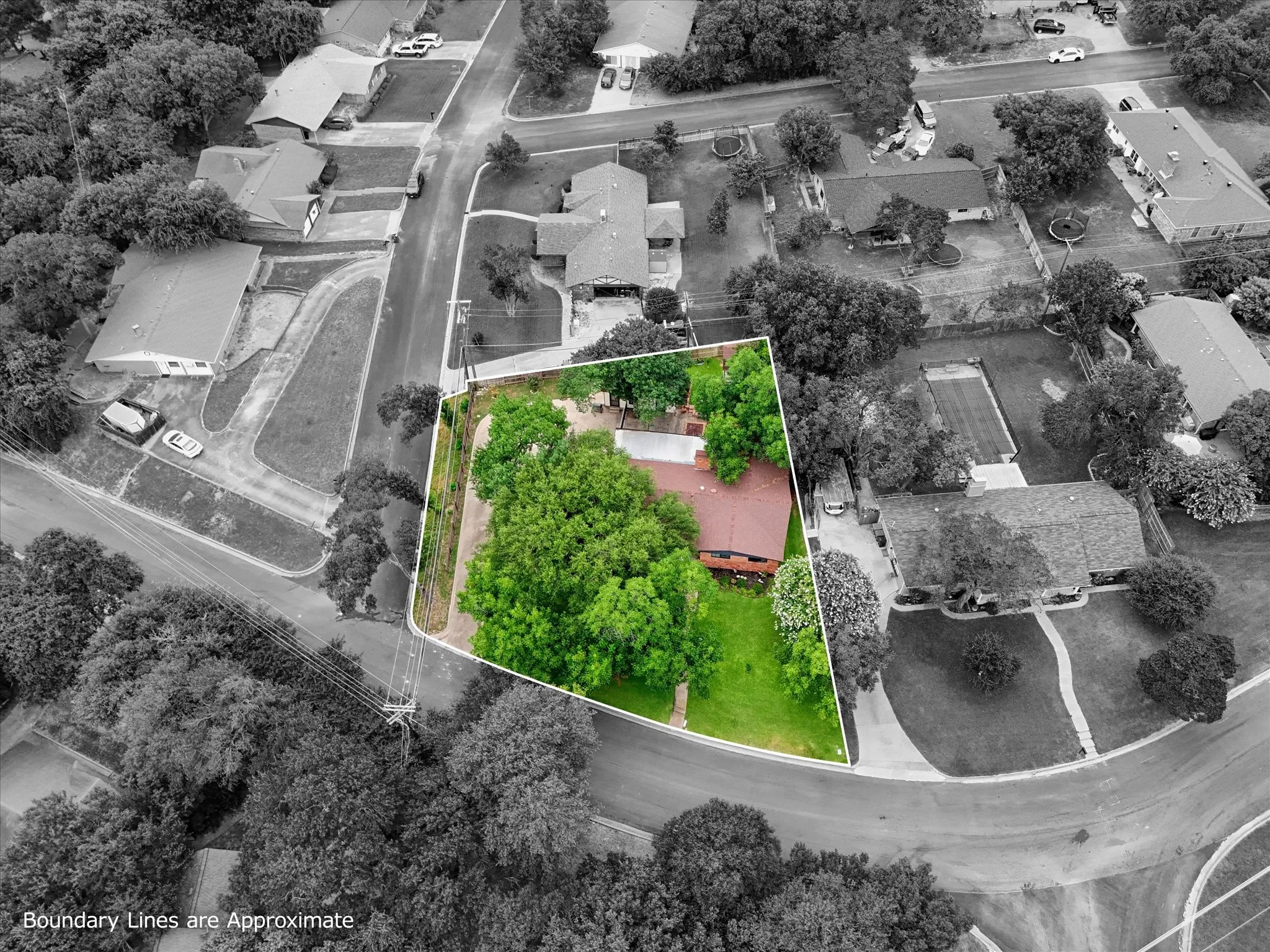 Aerial perspective showcasing a corner lot with mature trees, a red-toned roof, and a verdant lawn