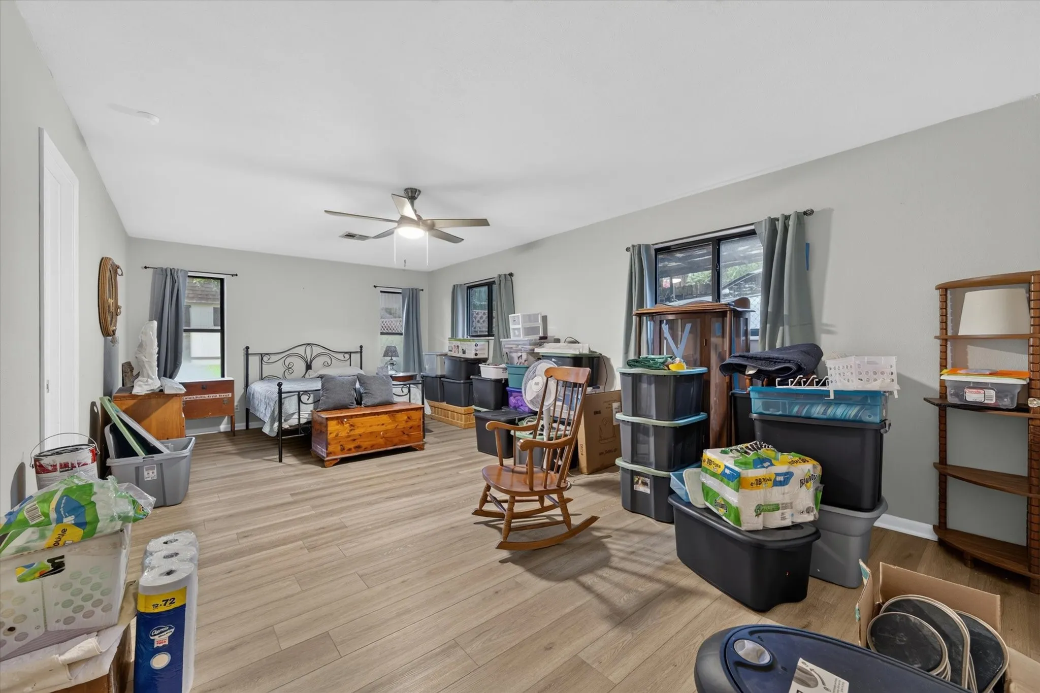 Spacious room featuring light gray wall paint and wood-finish flooring