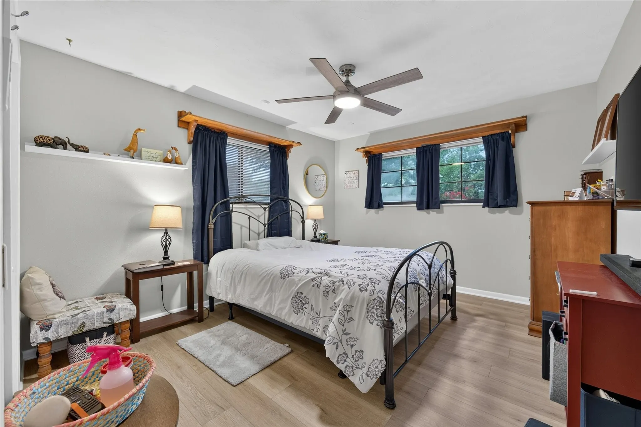 Spacious room with light wood-finish flooring, a ceiling fan with integrated lighting, and multiple windows