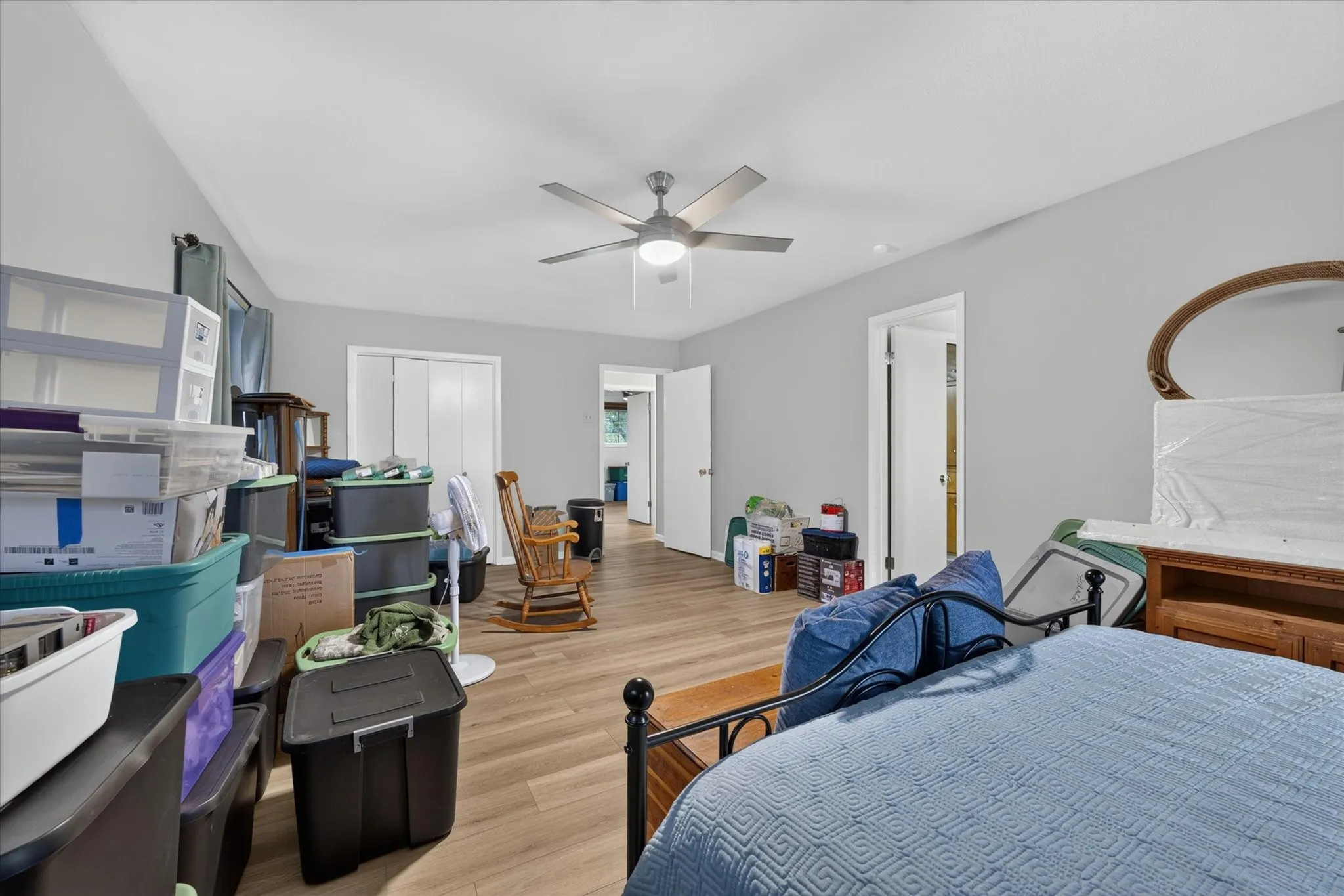 Spacious room featuring wood-finish flooring, light grey painted walls, a vaulted ceiling, and a ceiling fan with integrated lighting