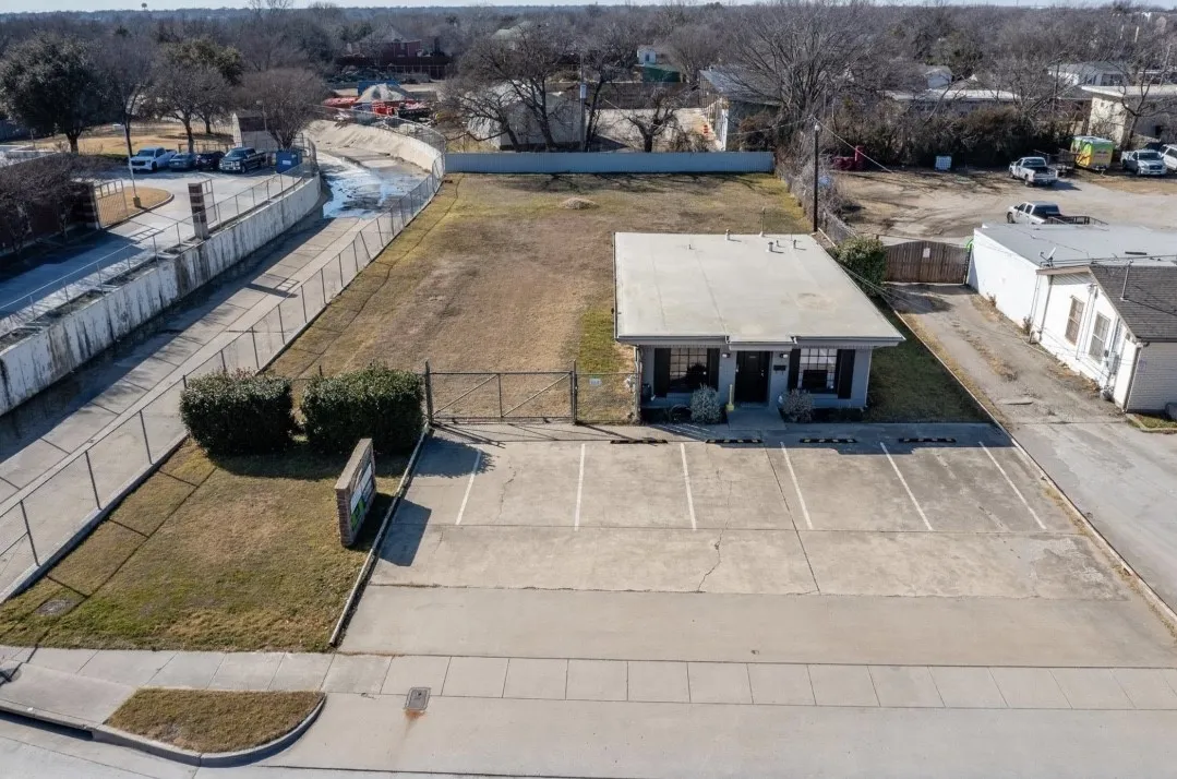 Commercial building with an extensive paved parking area, a large grassy lot, and mature landscaping