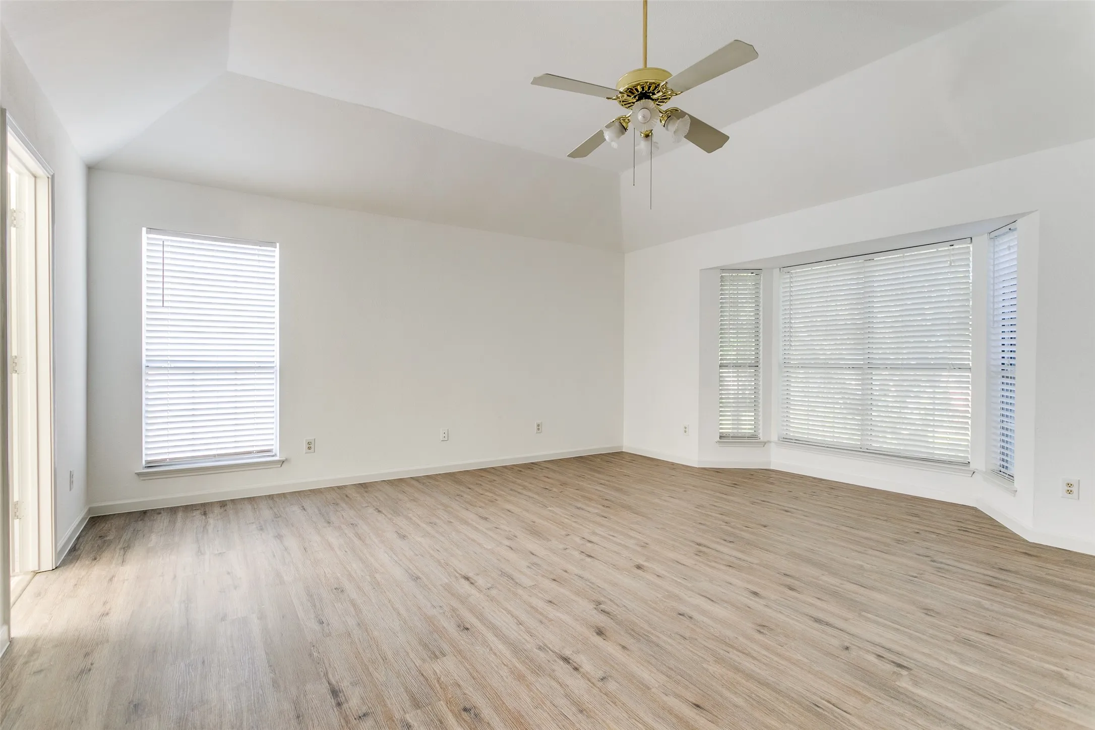 Empty room featuring light wood-type flooring, ceiling fan, and a wealth of natural light