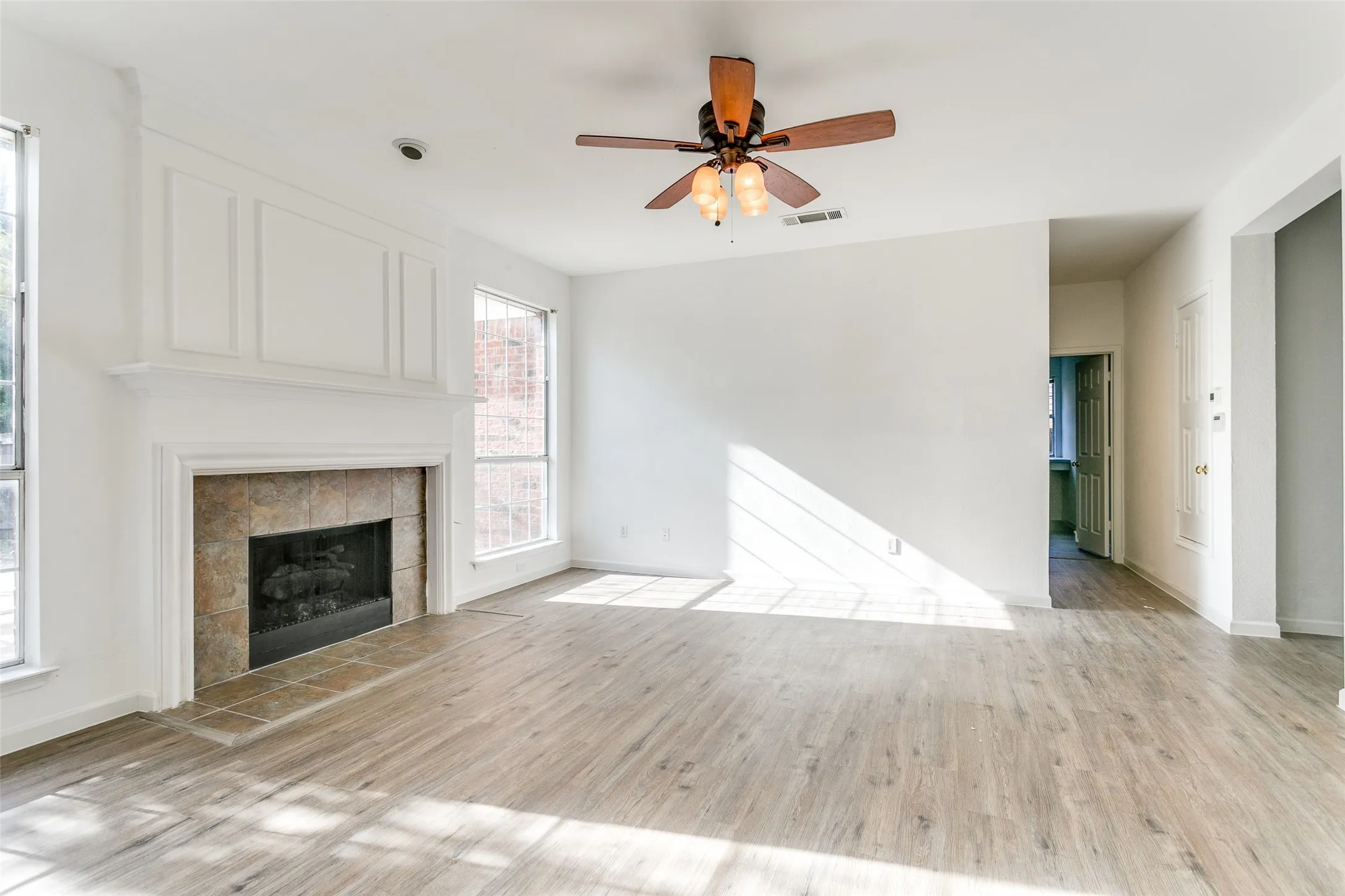 Unfurnished living room featuring a fireplace, light wood-type flooring, and ceiling fan