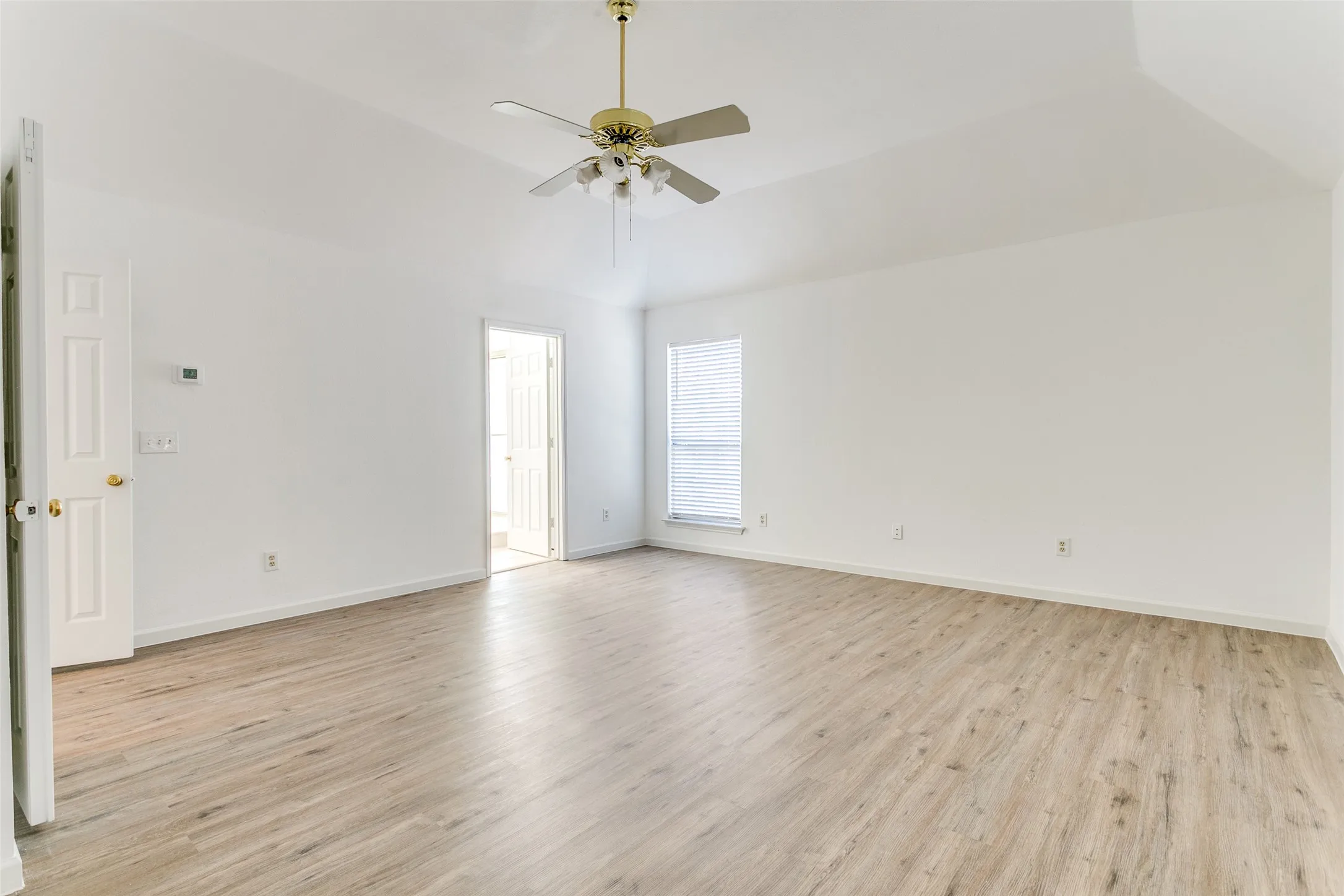 Empty room with vaulted ceiling, light wood-type flooring, and ceiling fan