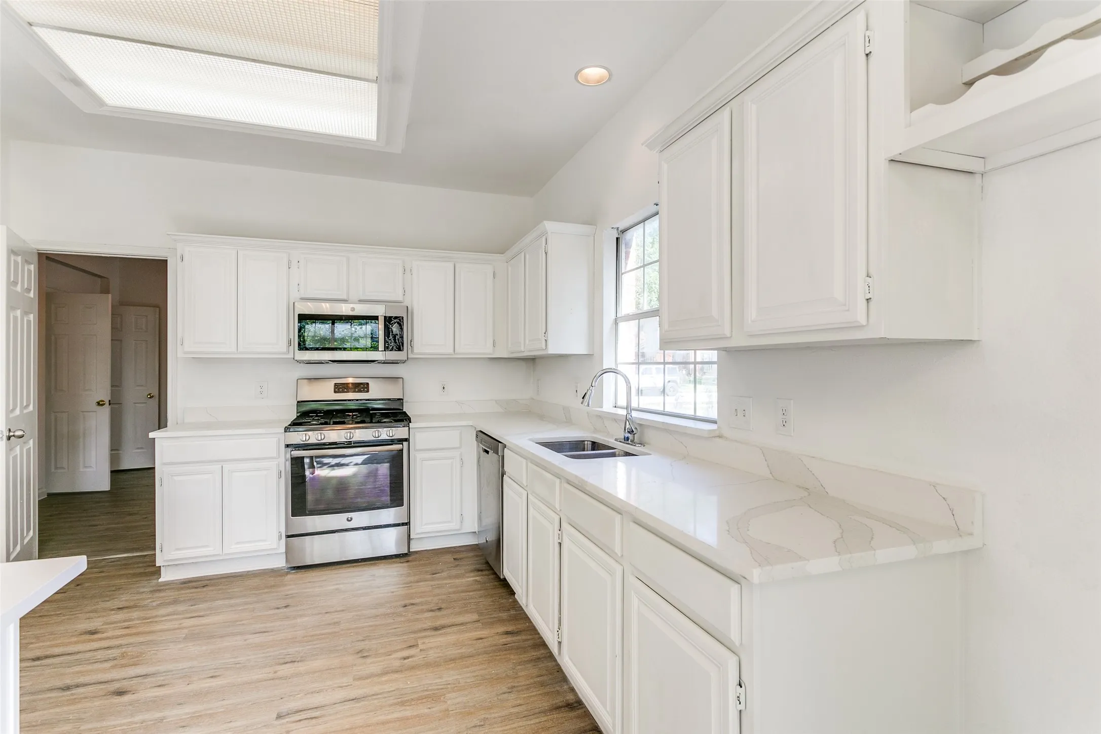 Kitchen with white cabinetry, light hardwood / wood-style flooring, appliances with stainless steel finishes, and sink
