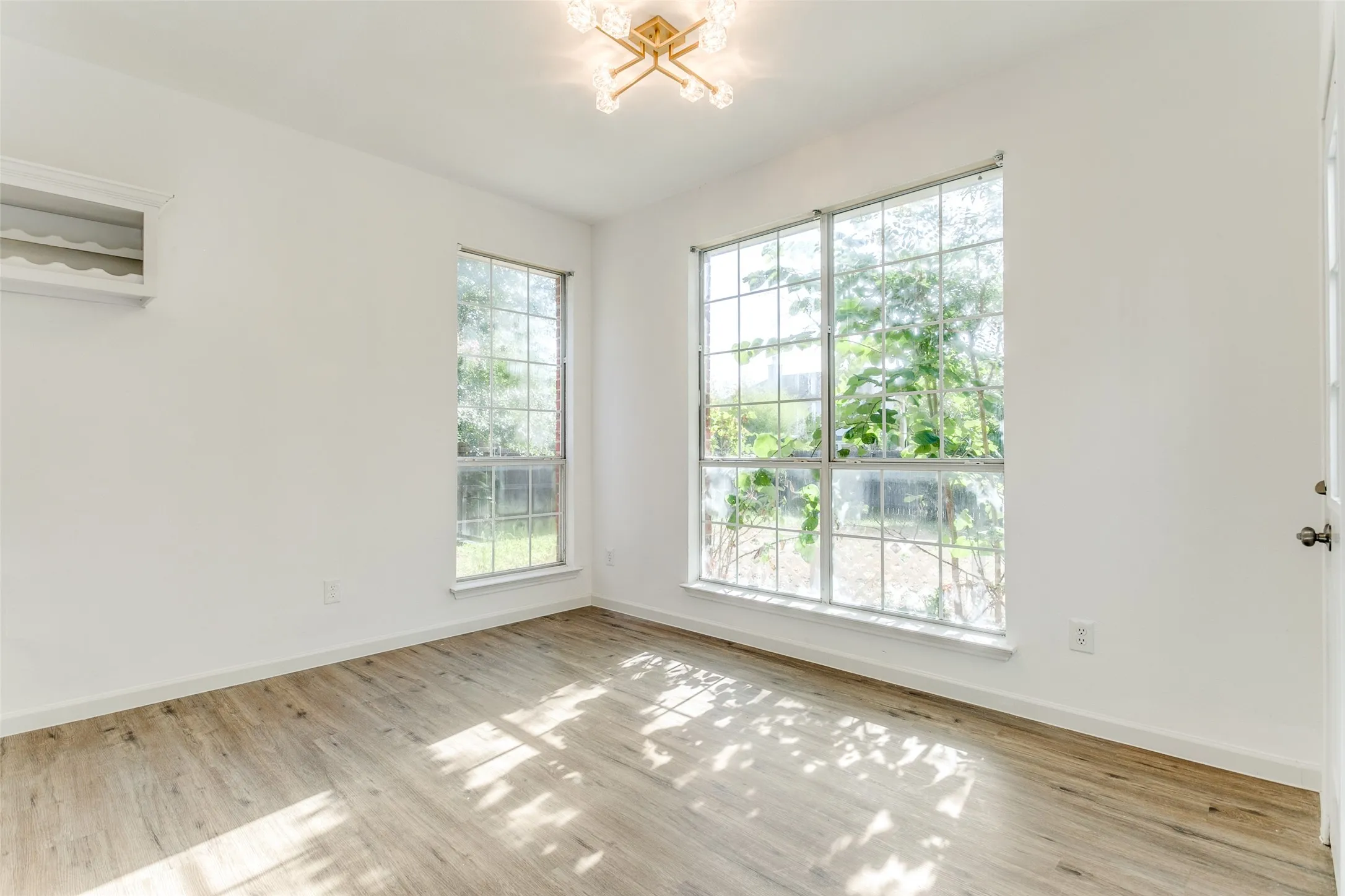 Spare room with light hardwood / wood-style flooring, a wealth of natural light, and a chandelier