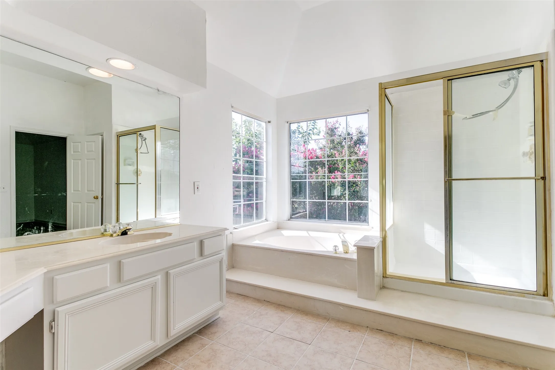 Bathroom with tile patterned flooring, lofted ceiling, independent shower and bath, and vanity