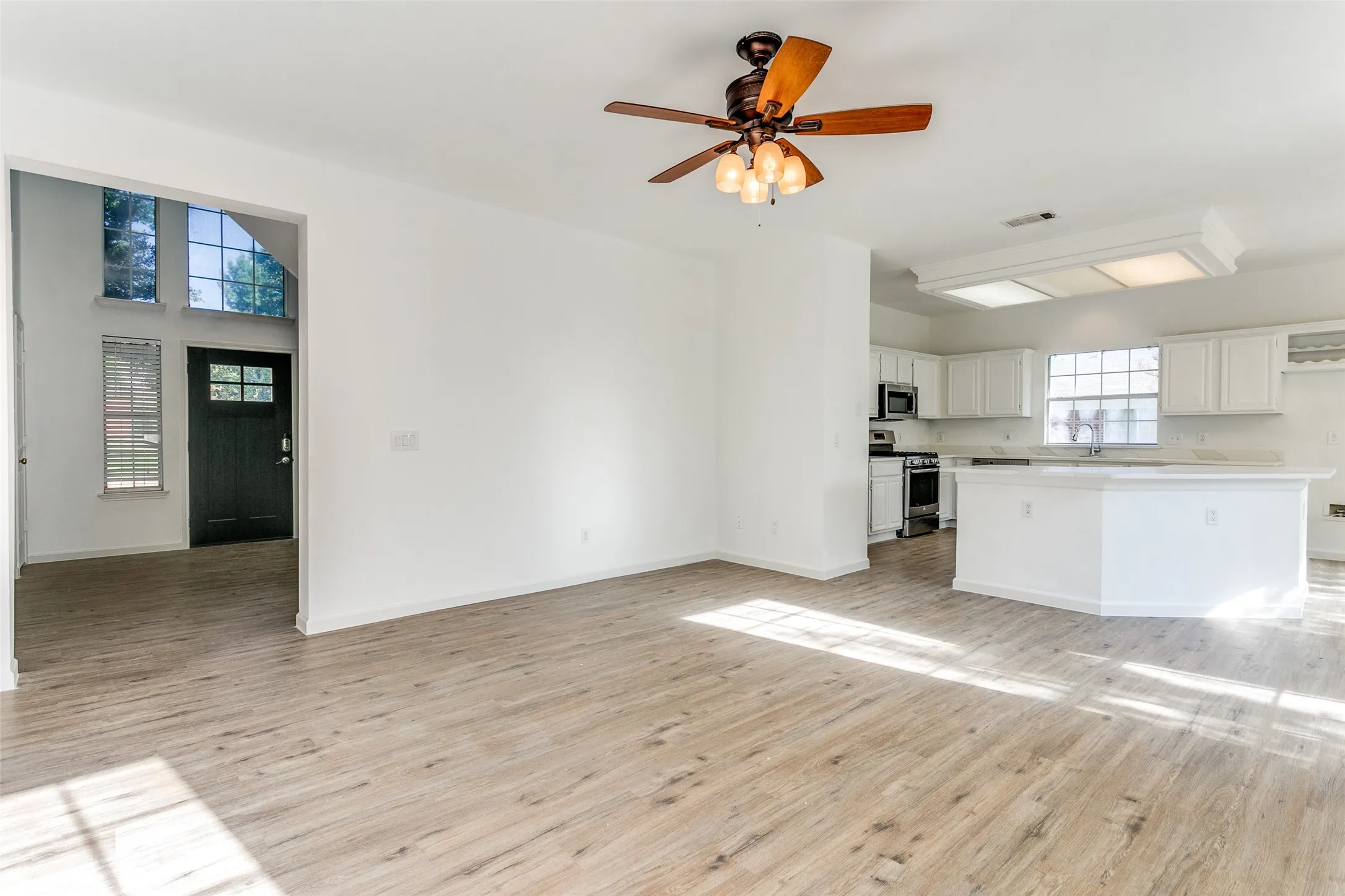 Kitchen featuring light wood-type flooring, ceiling fan, stainless steel appliances, and white cabinets