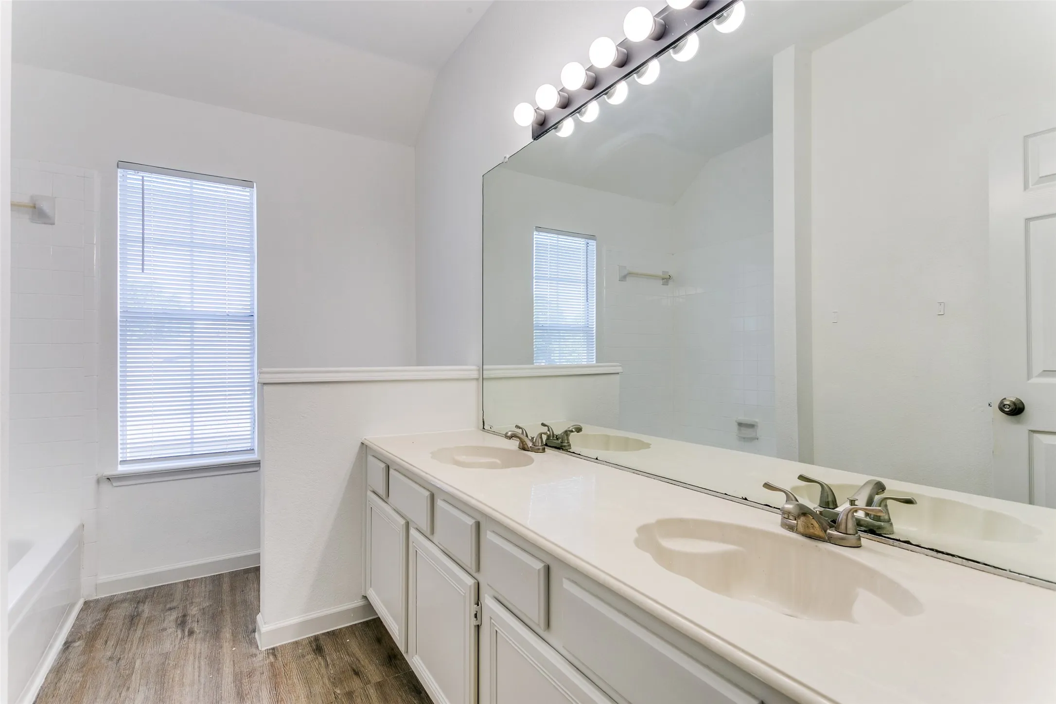 Bathroom featuring a healthy amount of sunlight, hardwood / wood-style flooring, and vaulted ceiling