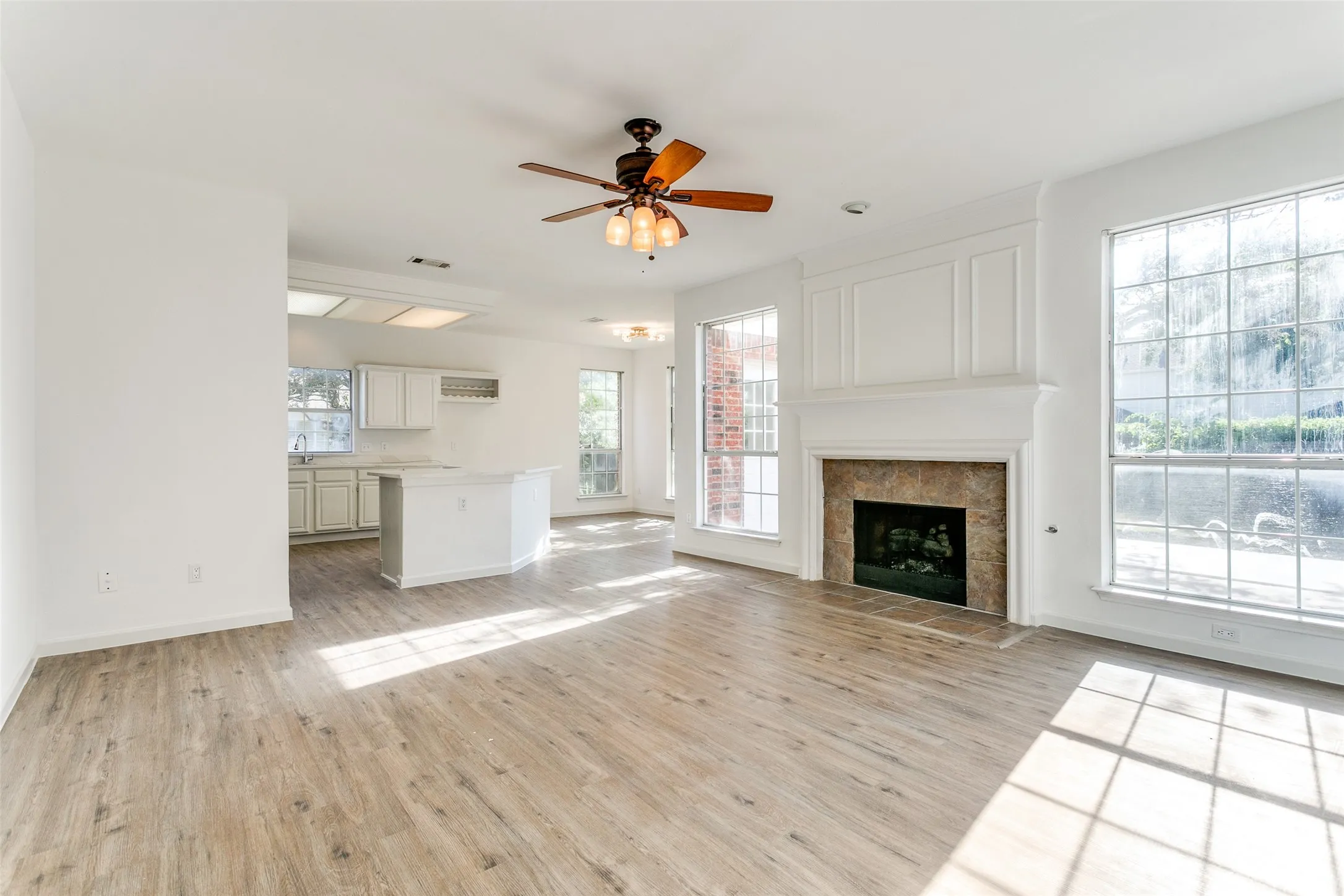 Unfurnished living room with a fireplace, light wood-type flooring, and ceiling fan