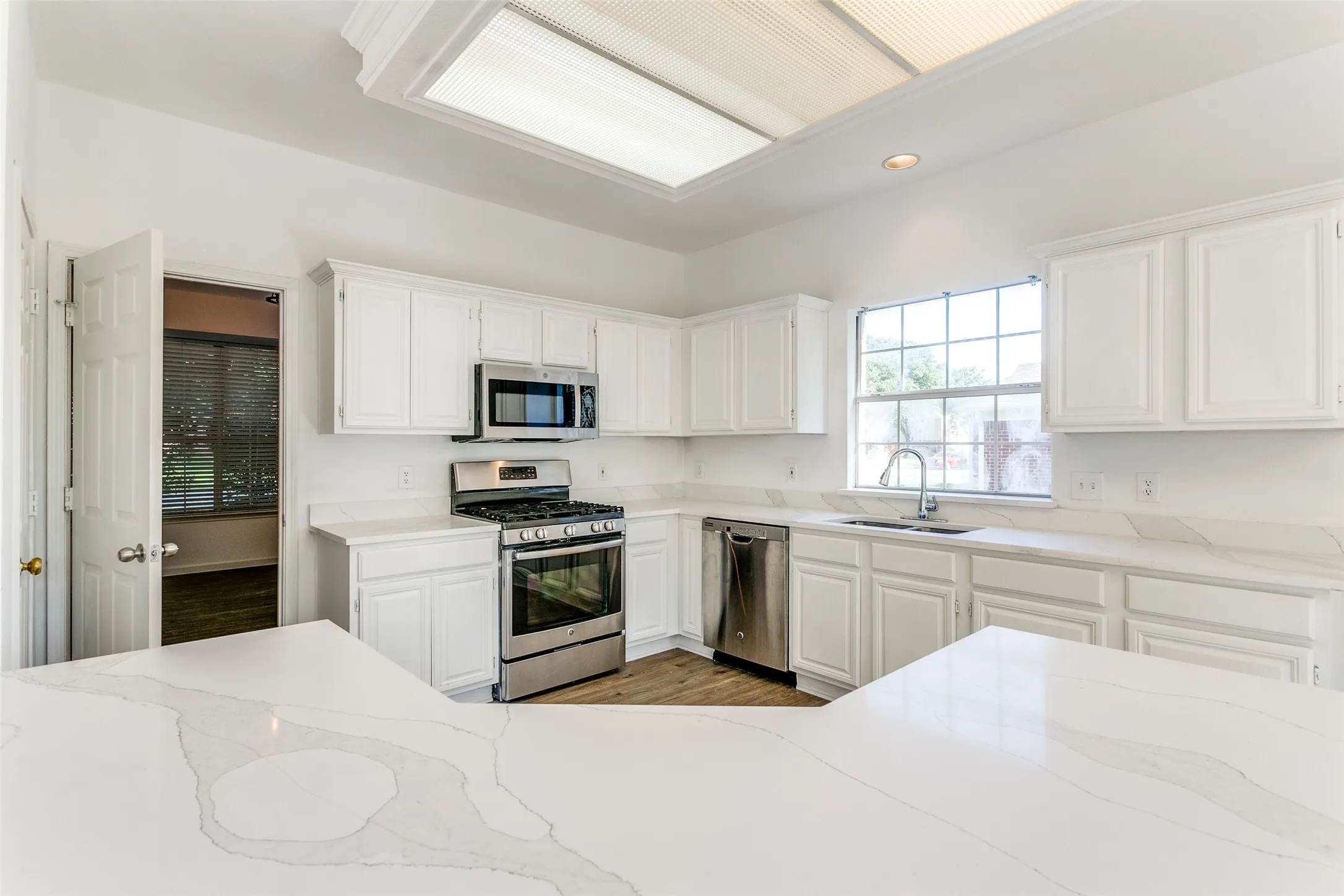 Kitchen with sink, light hardwood / wood-style flooring, white cabinetry, and stainless steel appliances