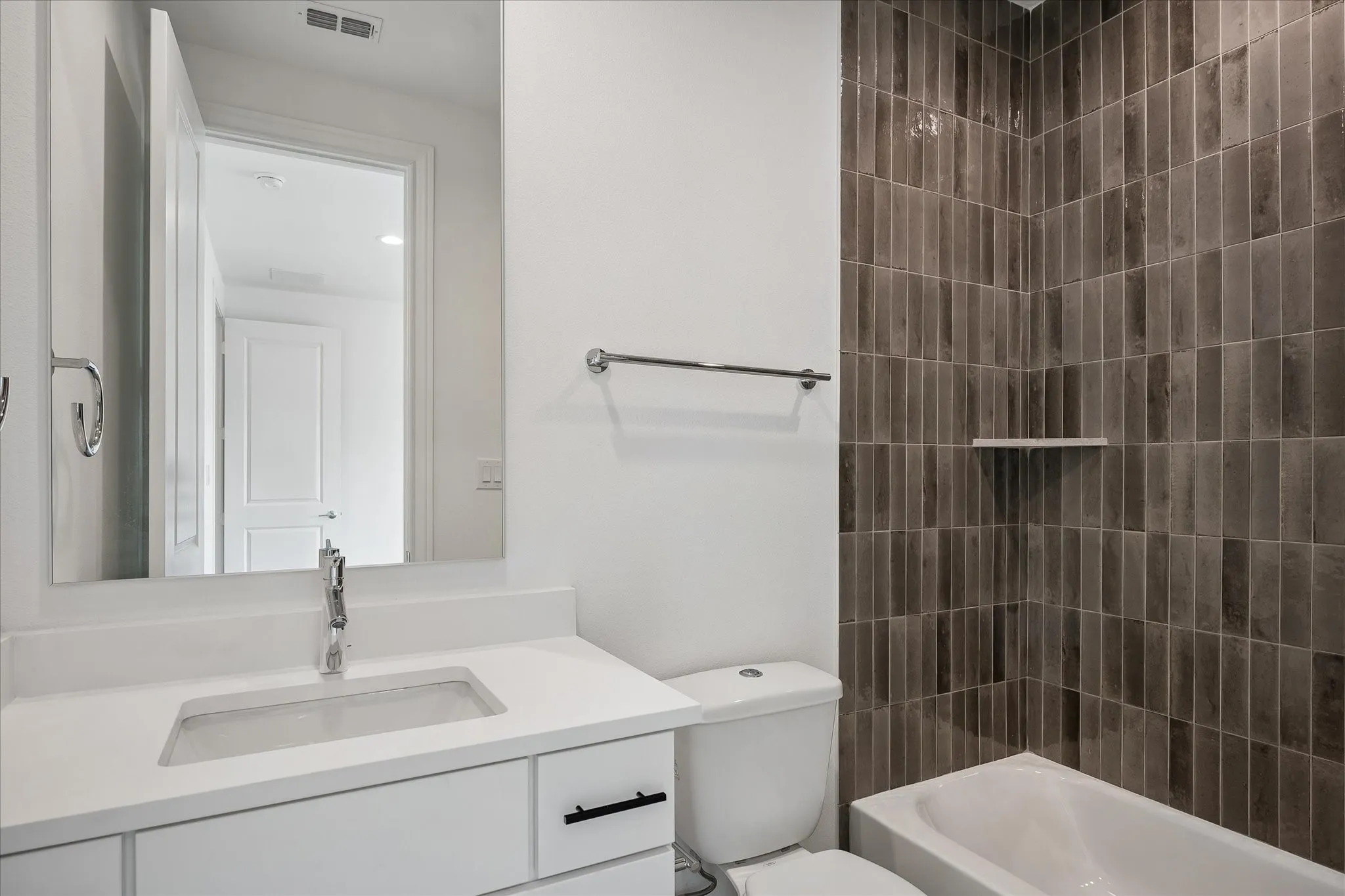 Modern bathroom featuring a floating vanity with white cabinetry, a rectangular undermount sink, and quartz countertop