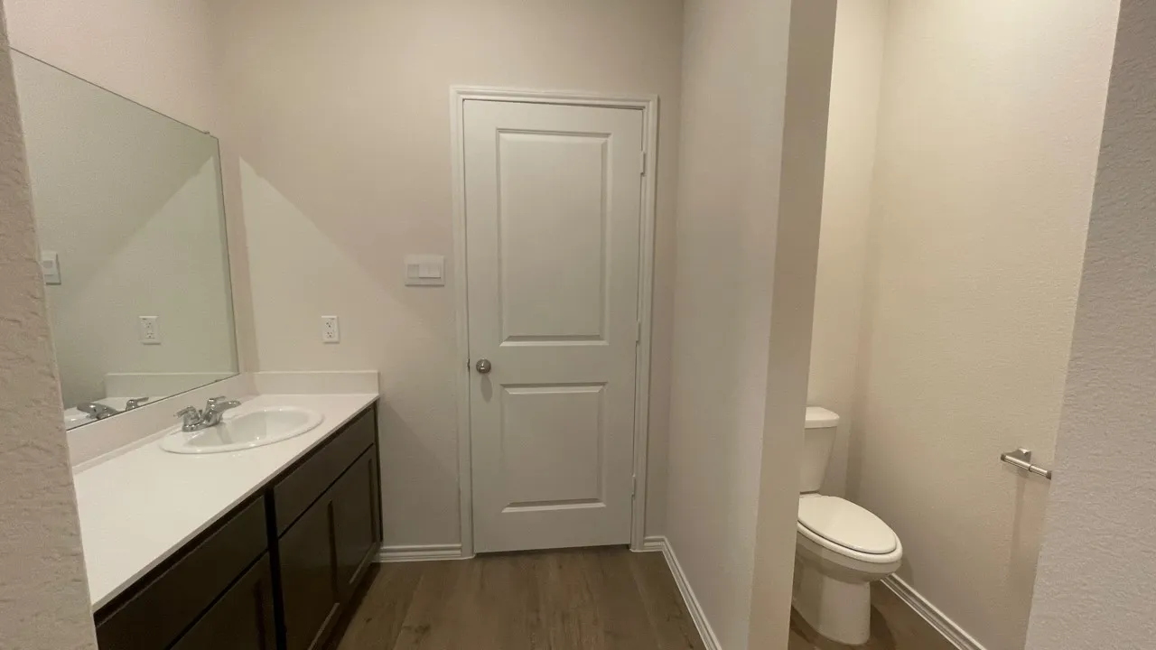 Bathroom featuring a vanity with an integrated sink, a large mirror, dark wood-finish cabinetry, and wood-finish flooring