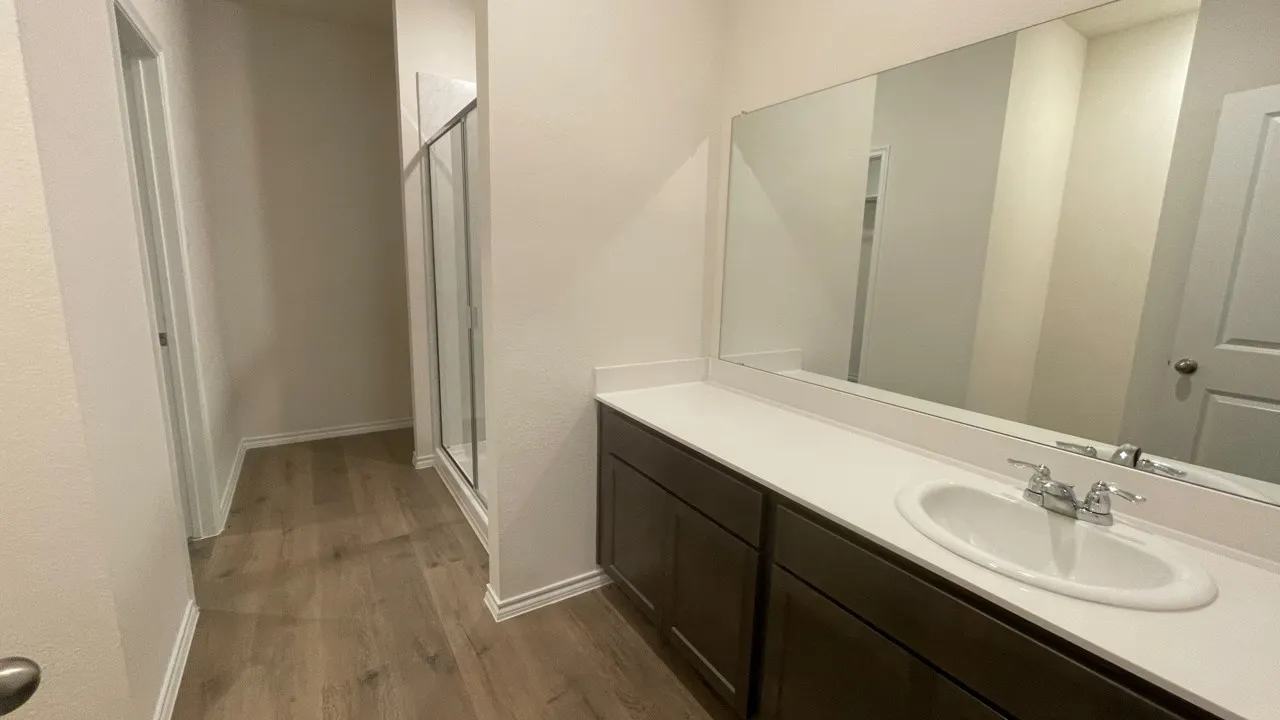 Bathroom vanity featuring a single-bowl sink, chrome faucet, white countertop, and dark wood-finish cabinetry