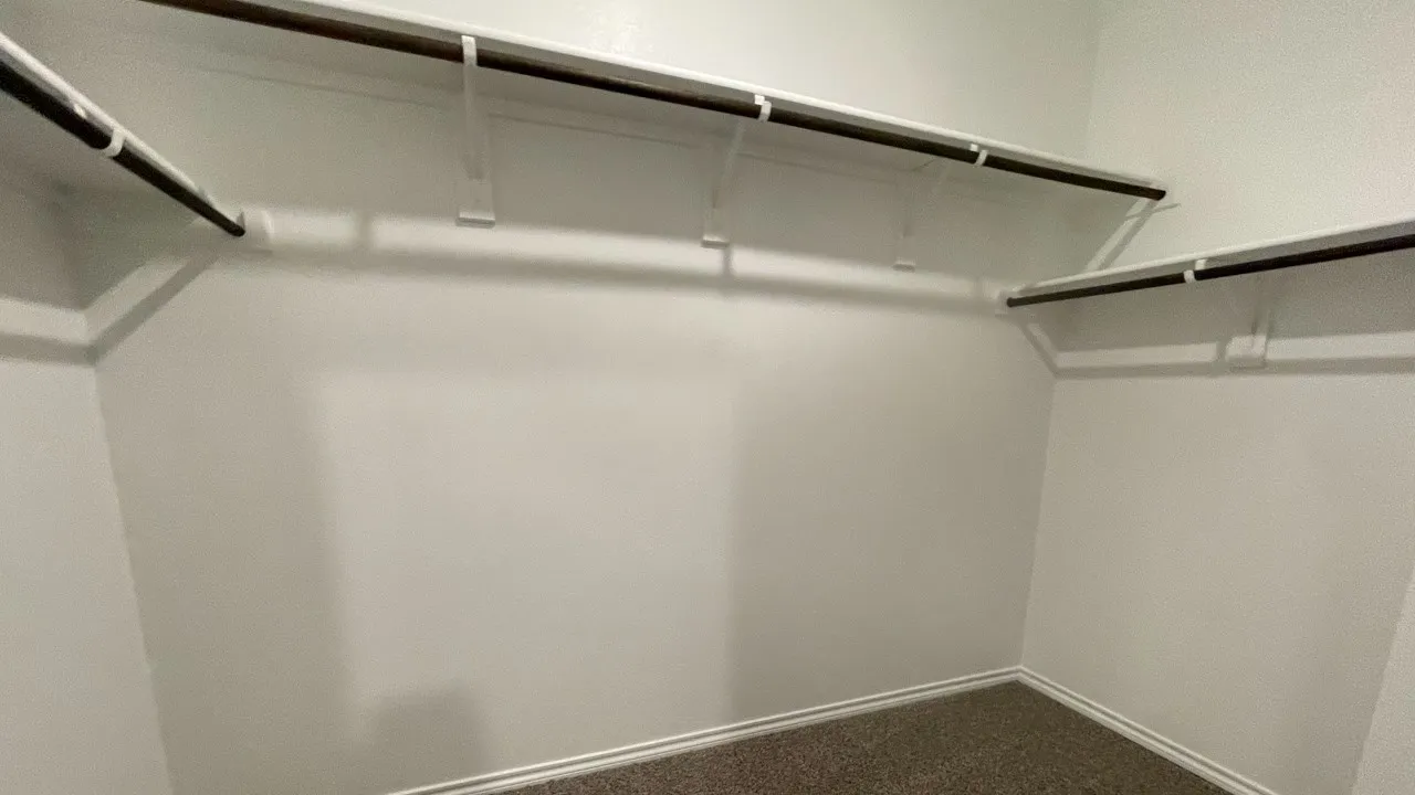 Walk-in closet featuring white painted walls and shelving with integrated hanging rods
