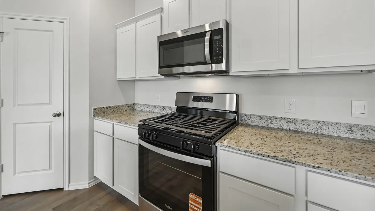 Kitchen featuring white shaker-style cabinetry, a stainless steel gas range, and a coordinating stainless steel microwave