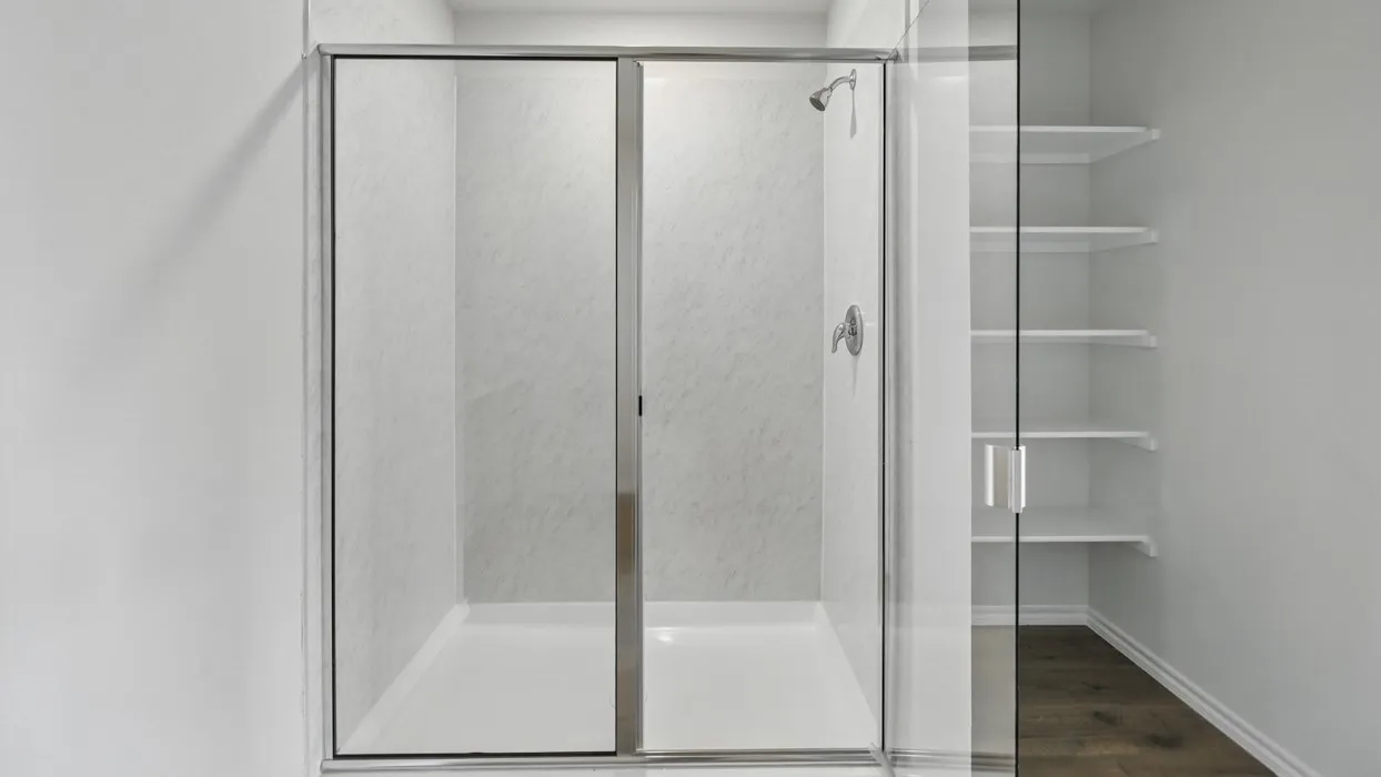 Glass-enclosed shower with a white shower base and white textured wall panels