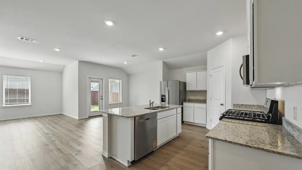 Kitchen island featuring a dual basin sink and dishwasher, complemented by wood-finish flooring, recessed lighting, and granite countertops