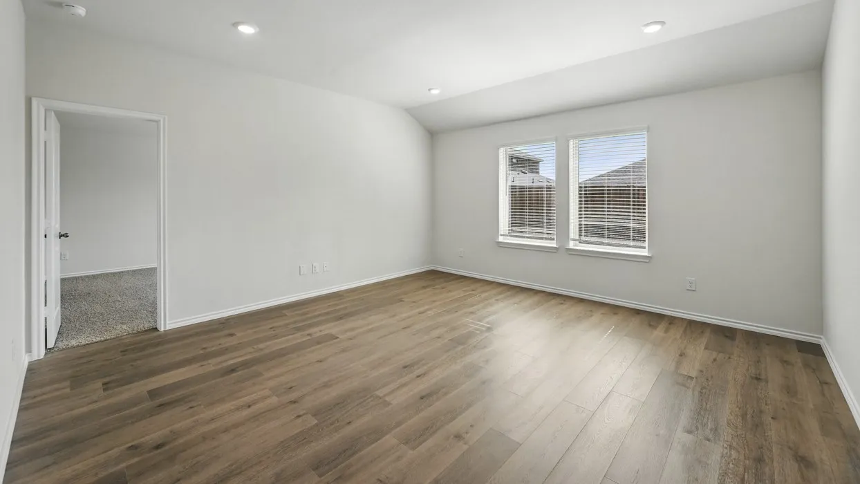 Spacious room featuring wood-finish flooring, two windows with blinds, recessed lighting, and a neutral color palette