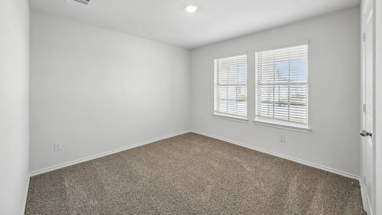 Bright room featuring two windows with white blinds, neutral carpet flooring, and a flush-mount ceiling light