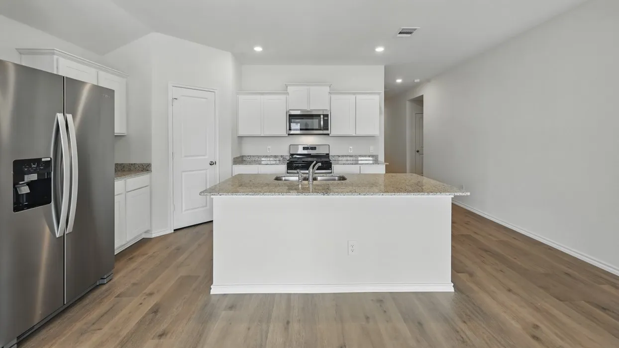 Kitchen featuring a central island with an undermount sink, ample cabinetry, stainless steel appliances, and wood-finish flooring throughout