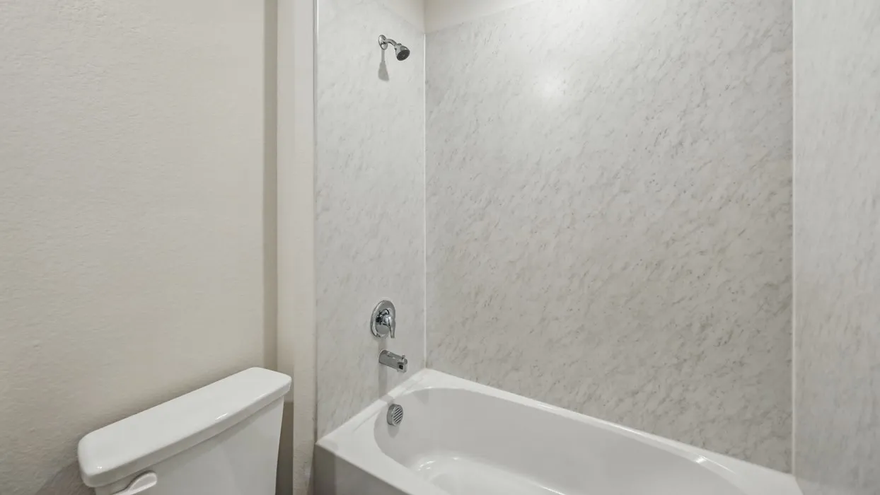 White tub and shower combination with a textured grey and white shower surround