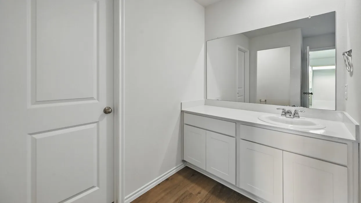 Bathroom vanity featuring a white countertop with an integrated sink, chrome faucet, and expansive wall-mounted mirror