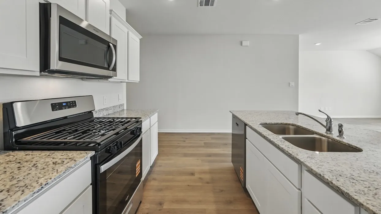 Modern kitchen featuring light-toned countertops, white cabinetry, stainless steel appliances, and wood-finish flooring