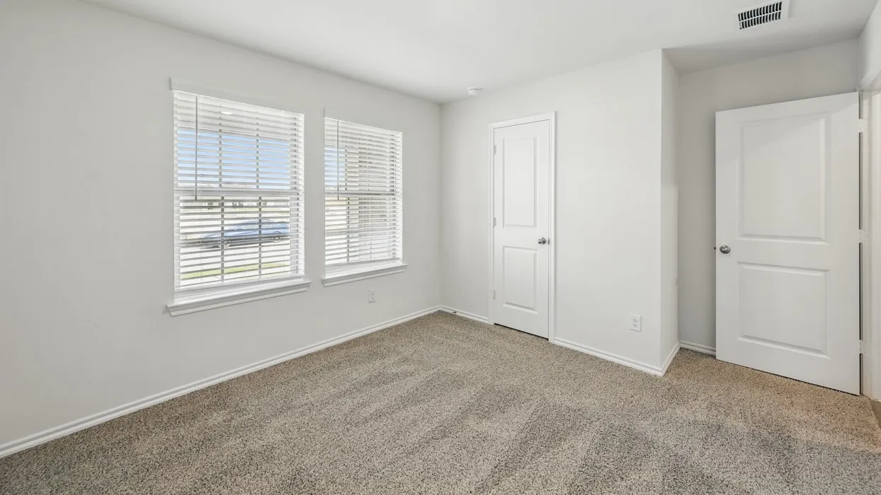 Neutral tone wall paint, dual windows with blinds, plush carpet flooring, white trim, and two panel doors