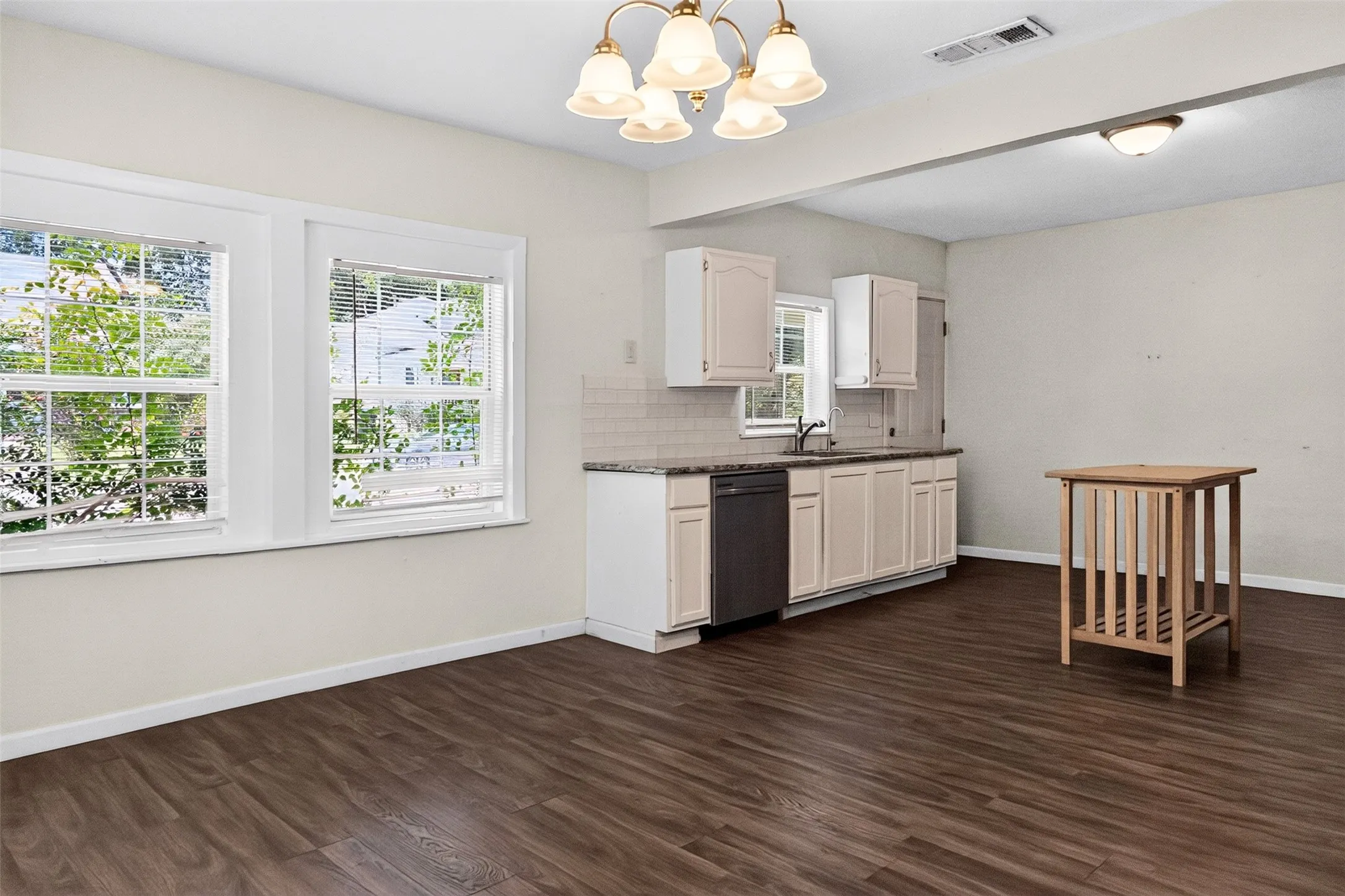 Open concept living space featuring wood-finish flooring and a kitchen area with white cabinetry