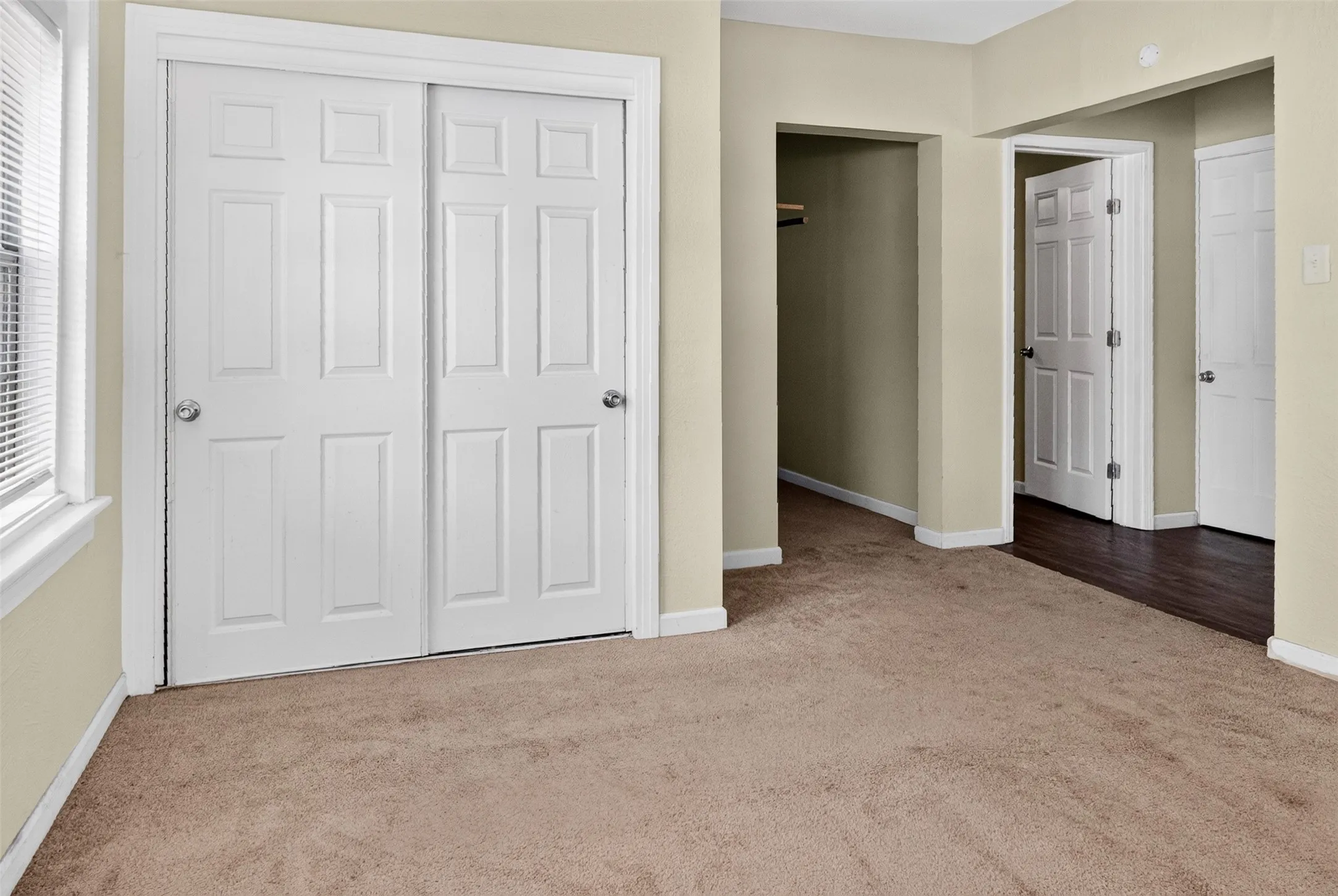 Carpeted interior space featuring a double-paneled bi-fold closet, neutral wall paint, and white trim