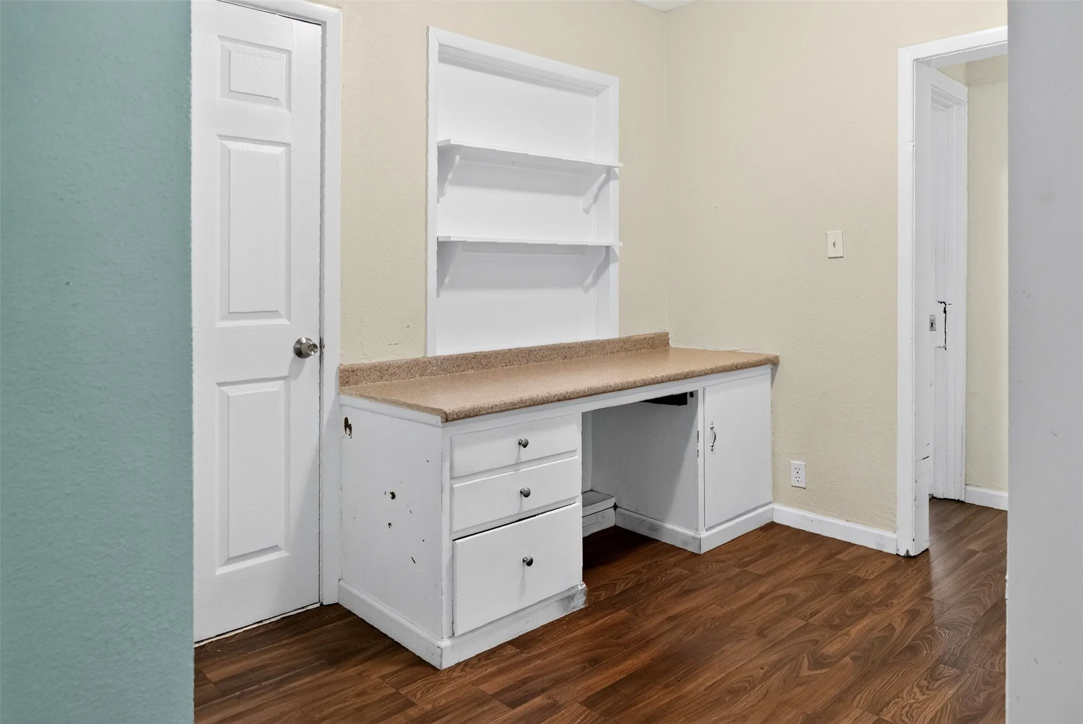 Built-in desk with a light-toned countertop, white cabinetry with silver-tone hardware, and integrated shelving